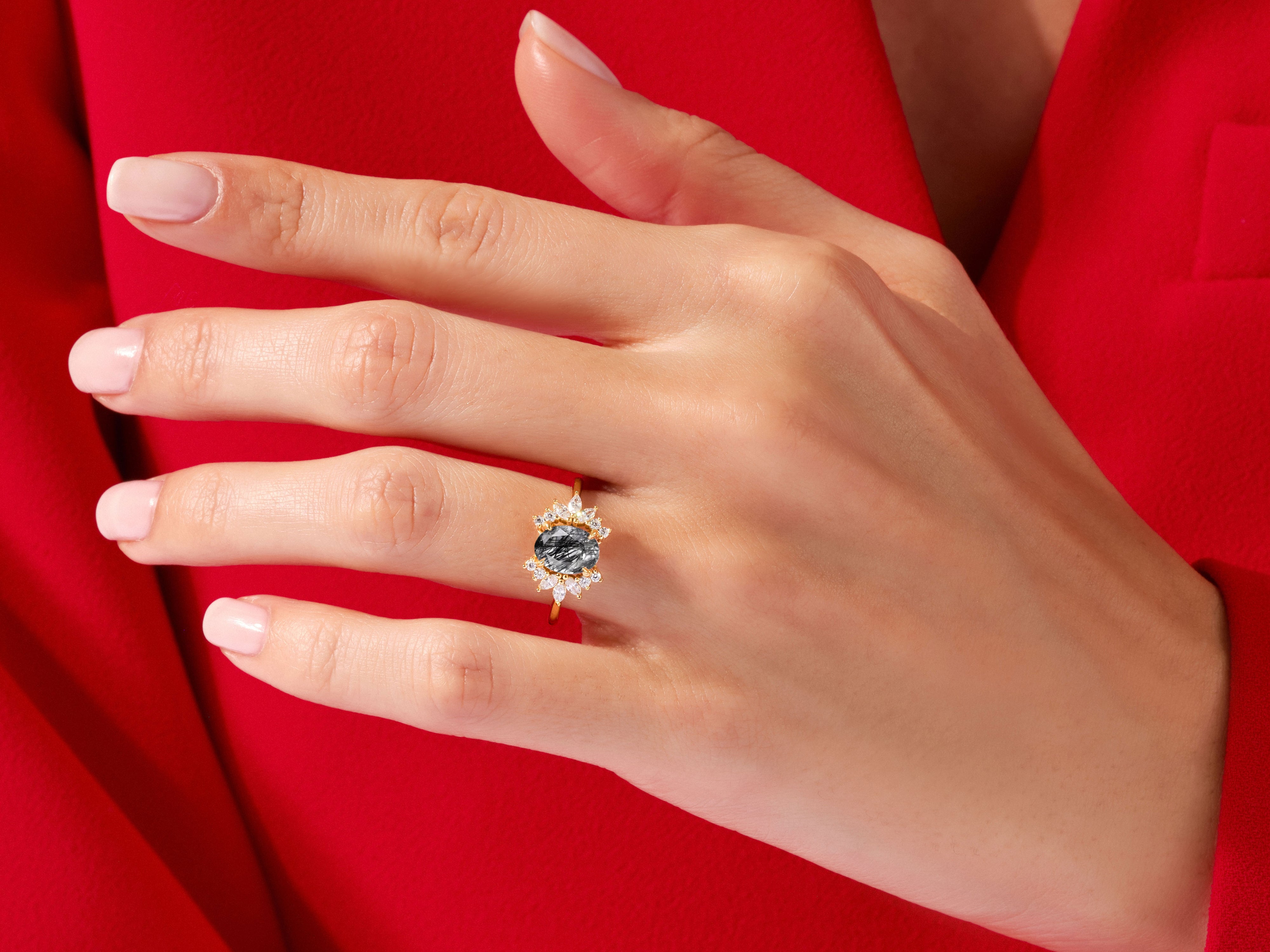 Gold ring with oval black stone and diamond halo on hand