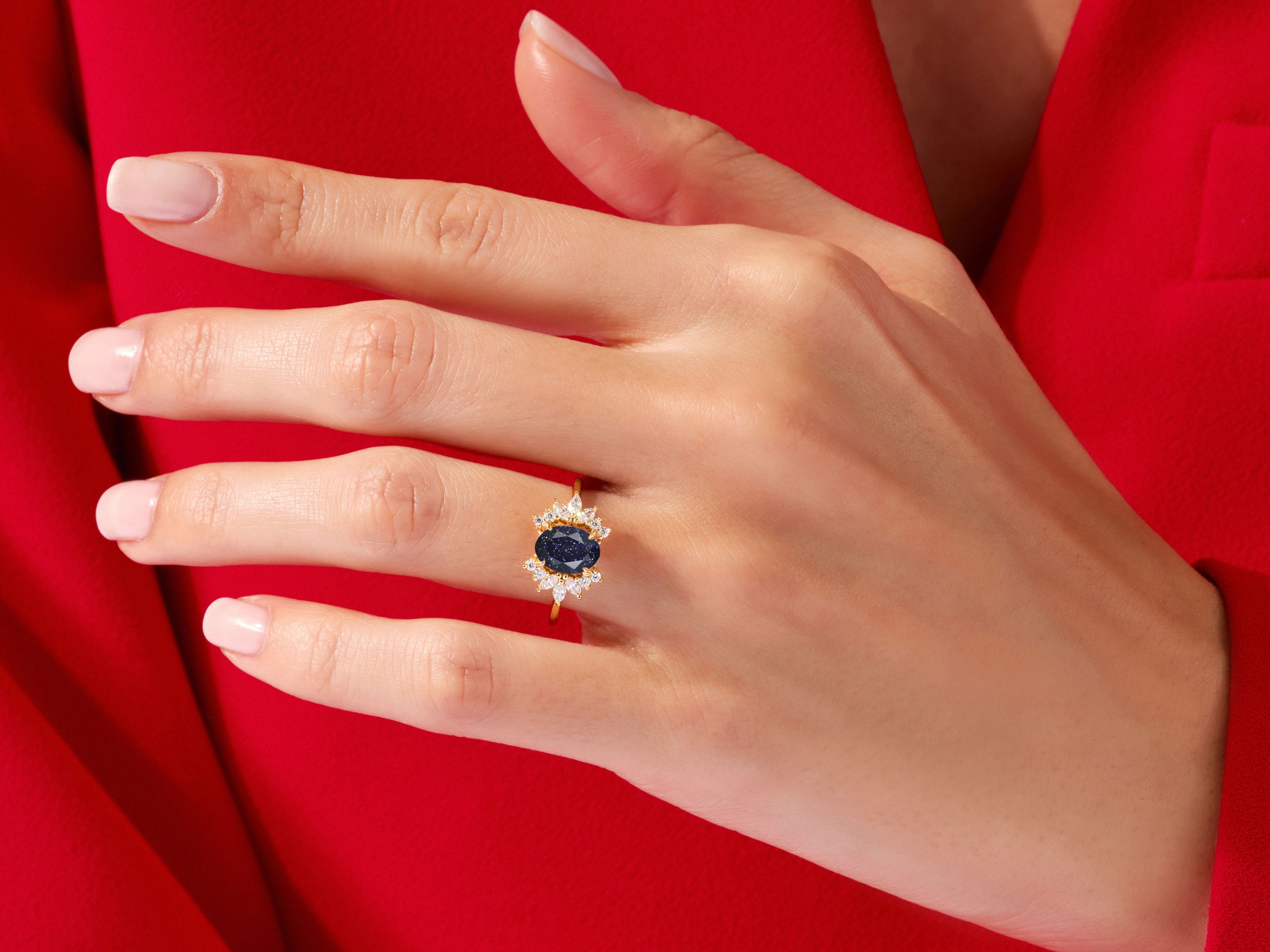 Gold ring with dark blue oval stone and diamonds on hand