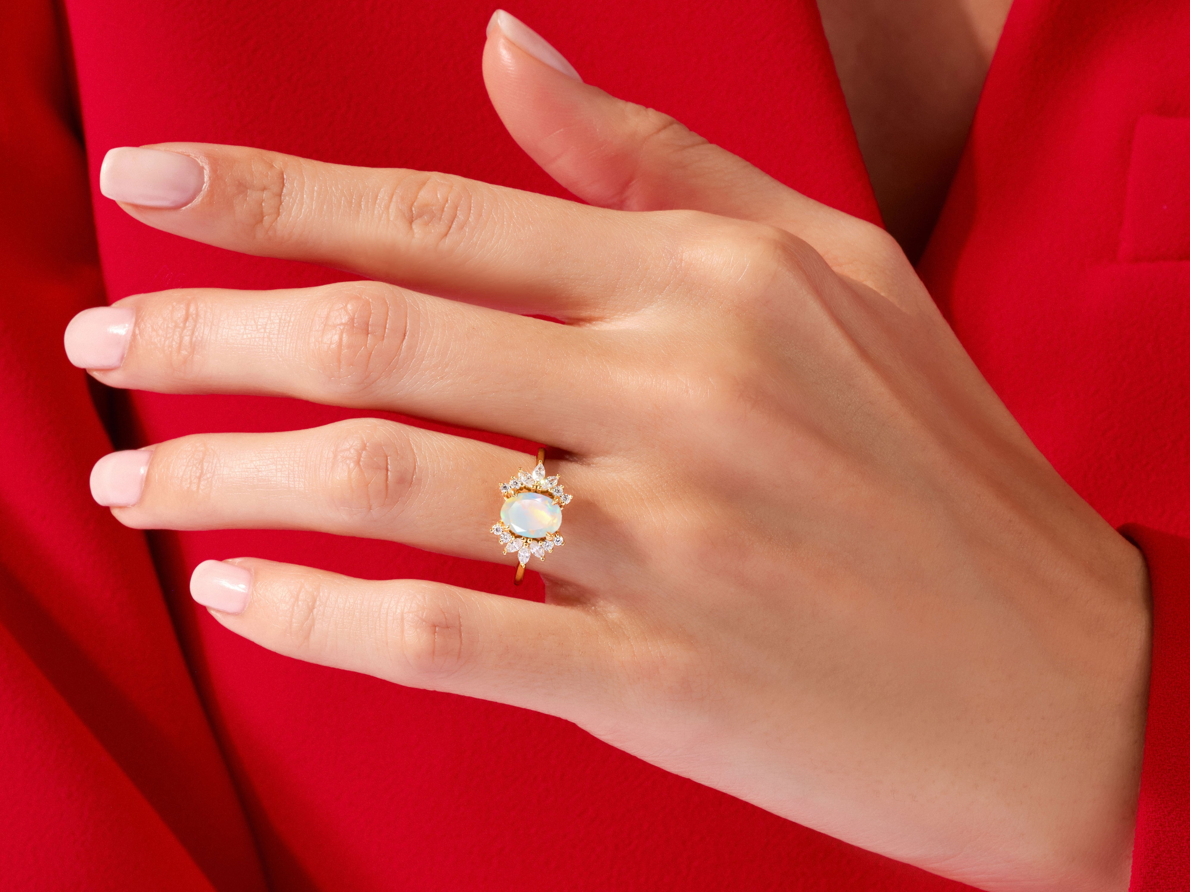 Gold opal and diamond halo ring on a hand
