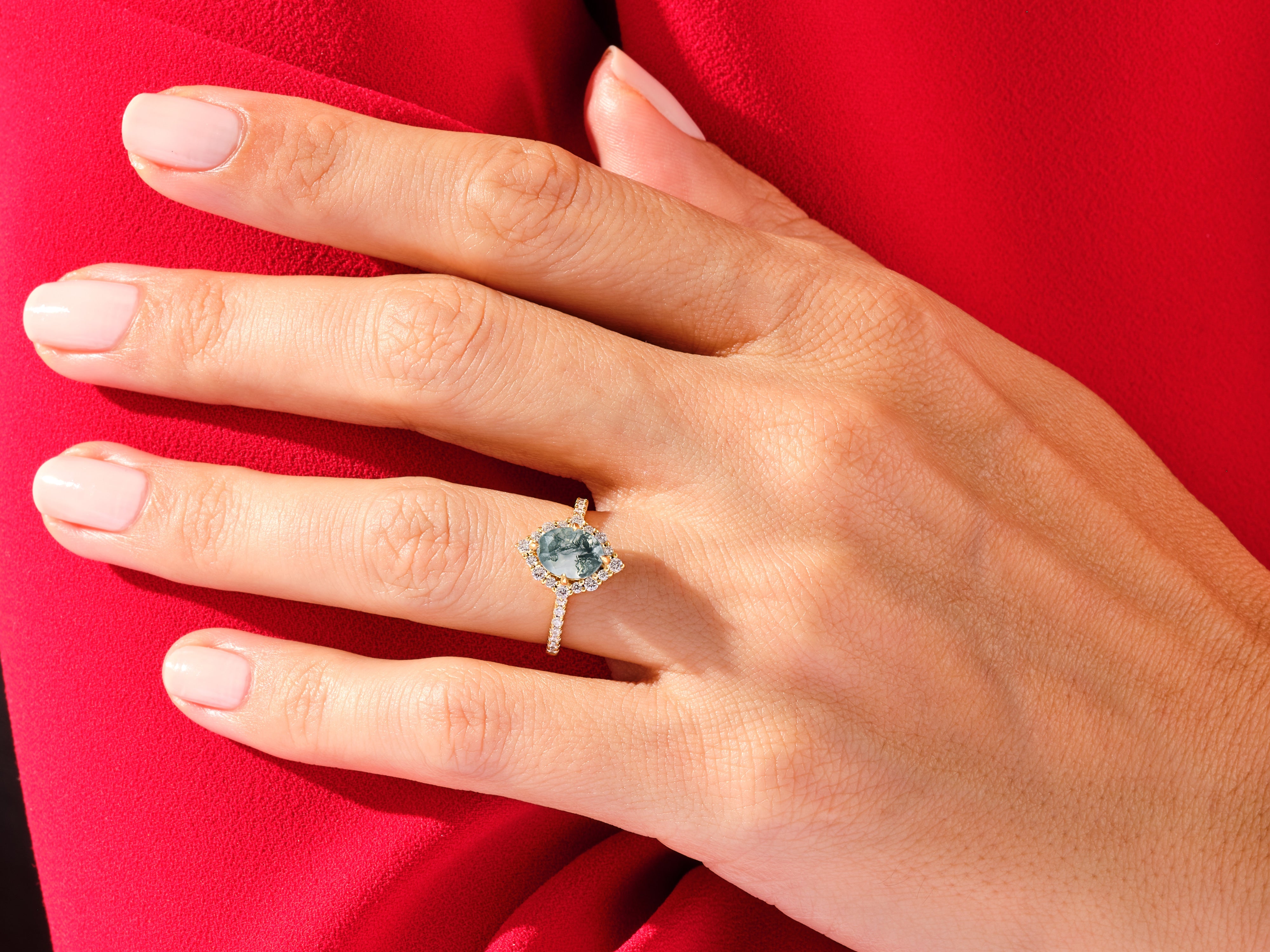 Moss agate engagement ring with diamonds on a red background