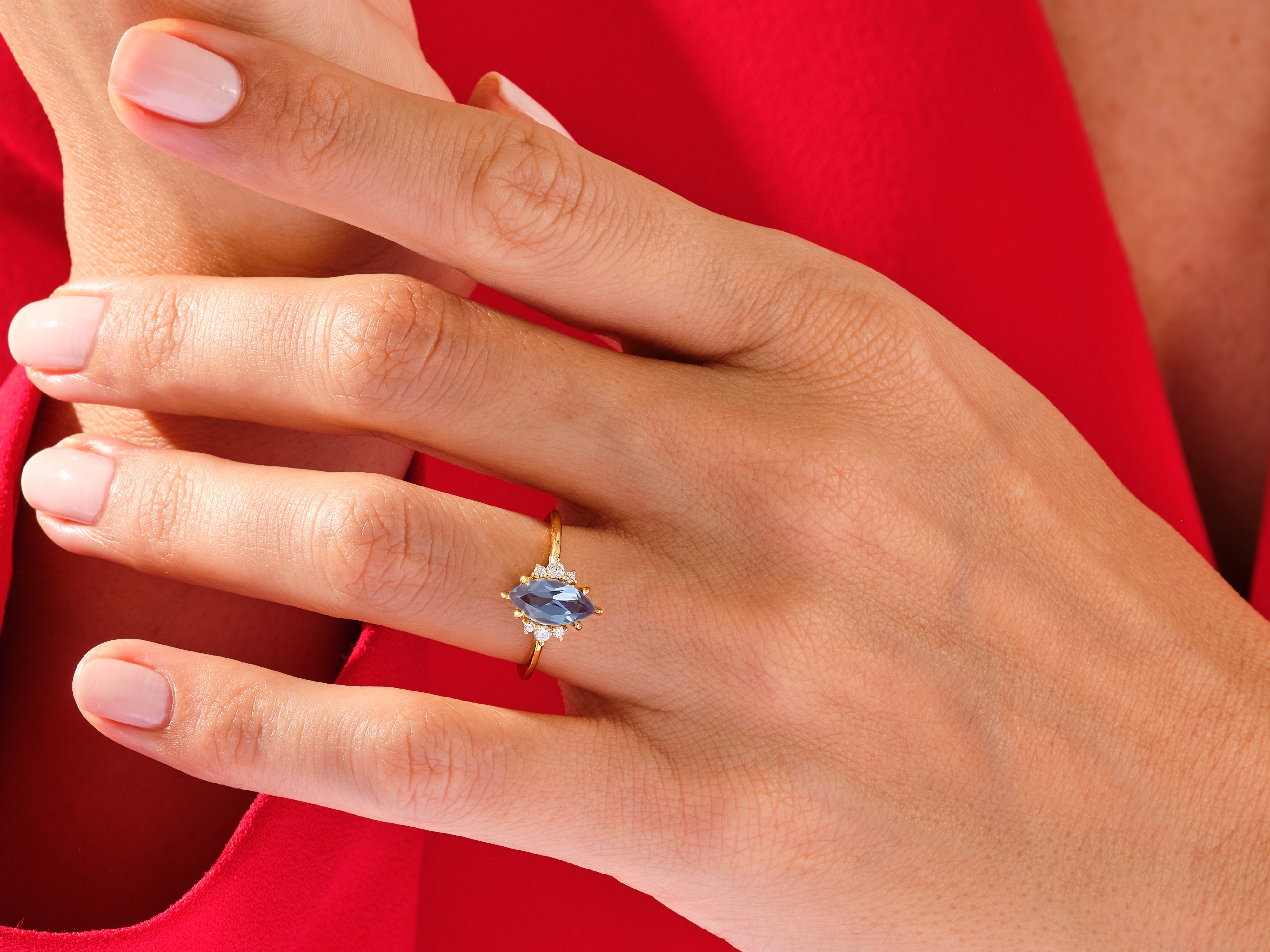Marquise blue gemstone ring with diamonds on a hand