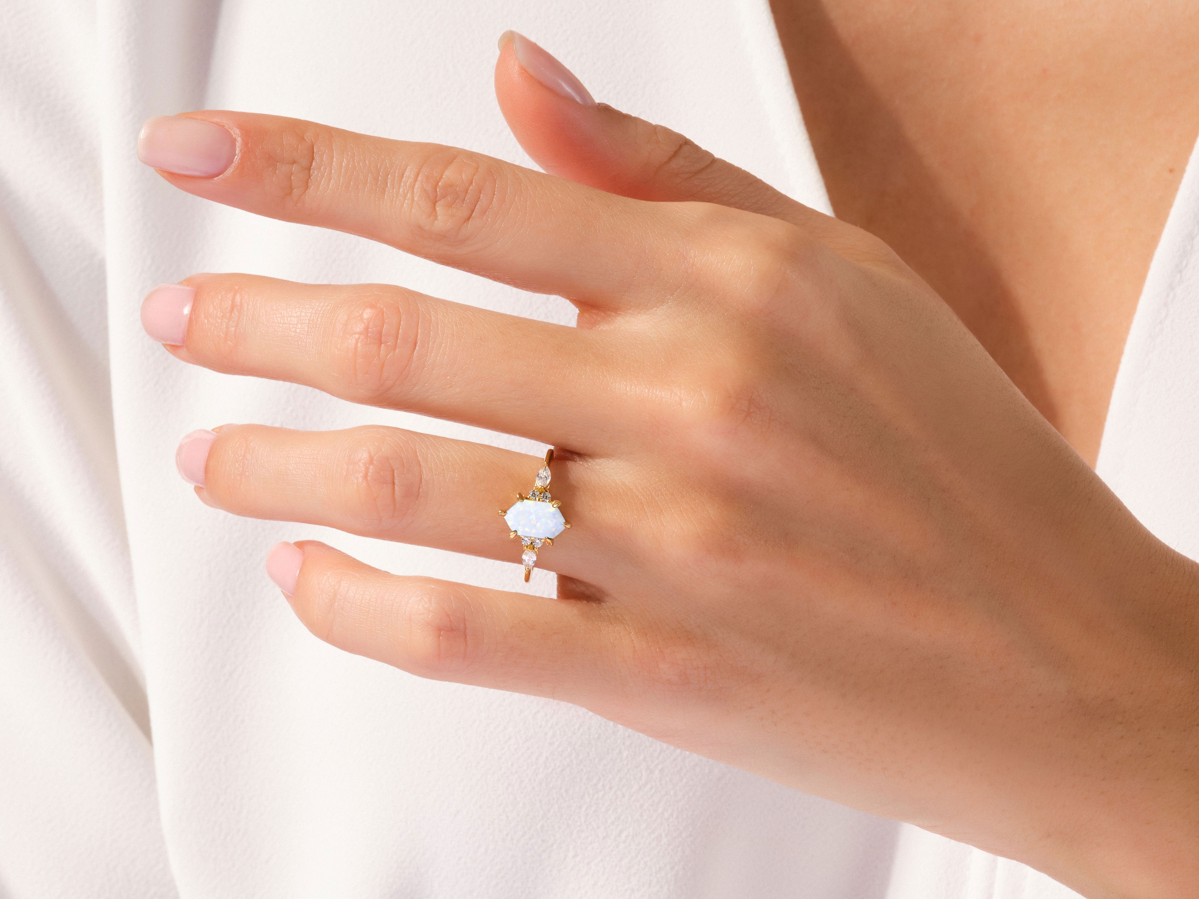 Gold opal ring with diamonds on a hand