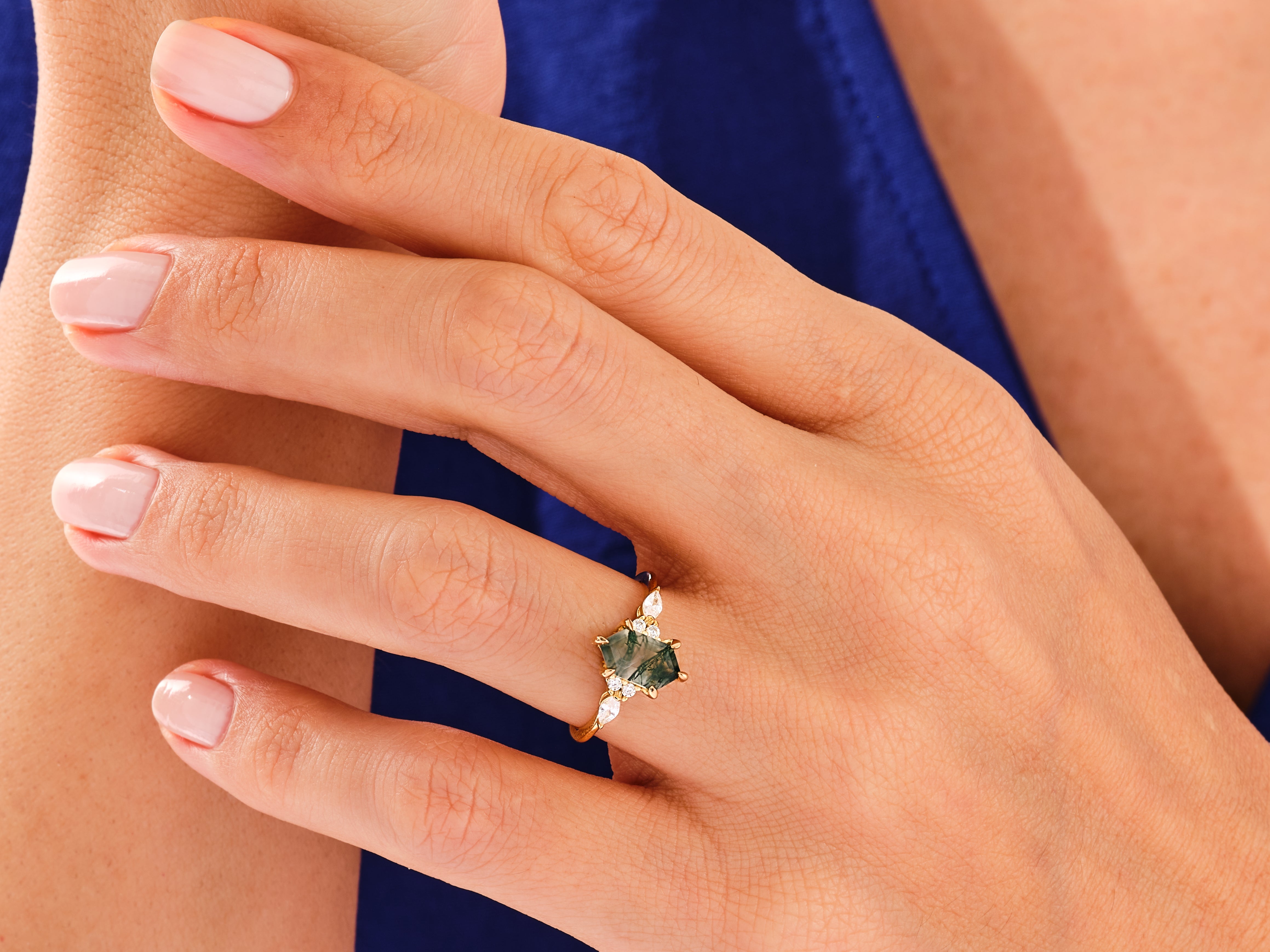 Gold ring with moss agate and diamonds on a woman's hand