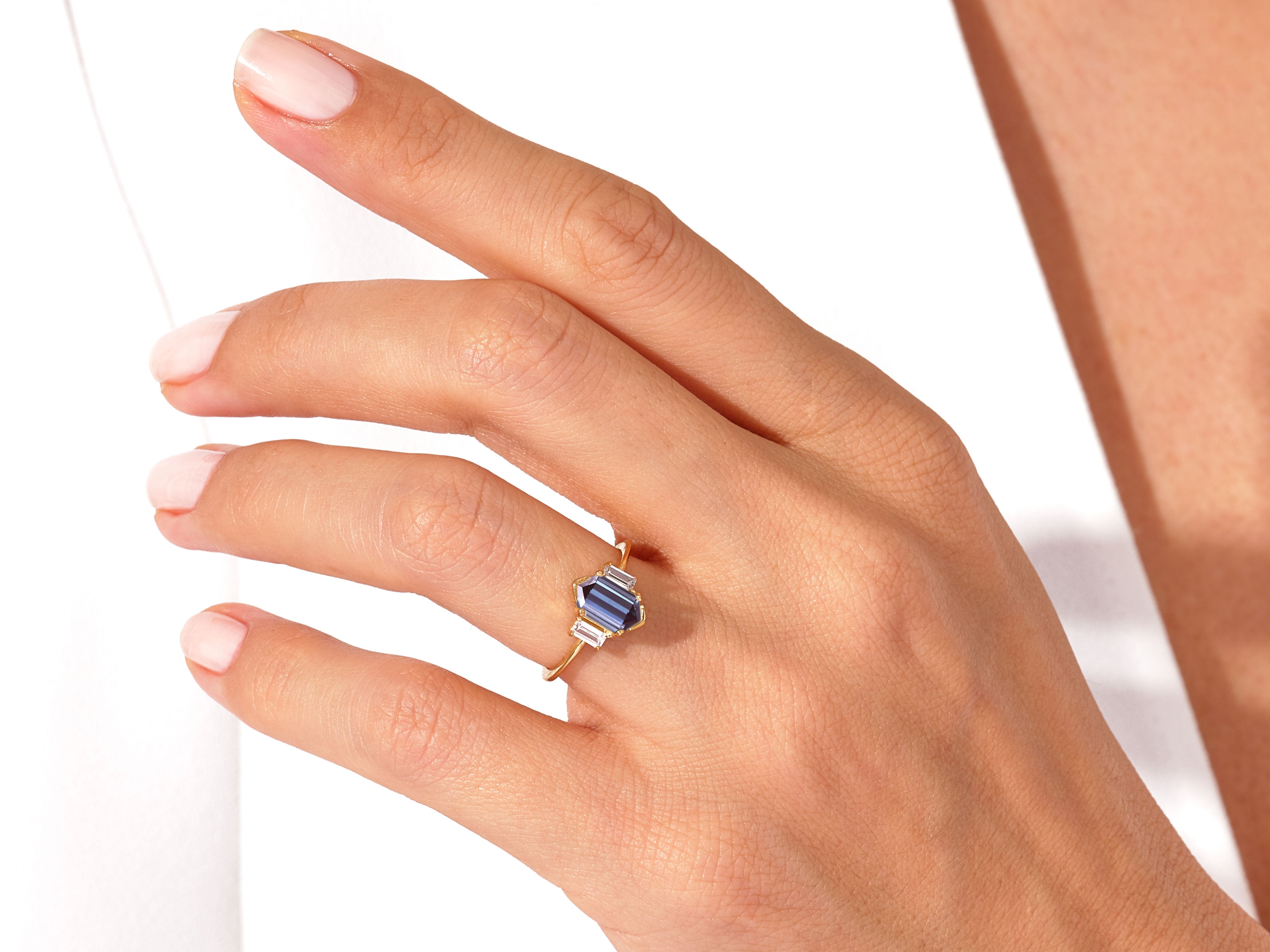 Gold ring with sapphire and baguette diamonds on a hand