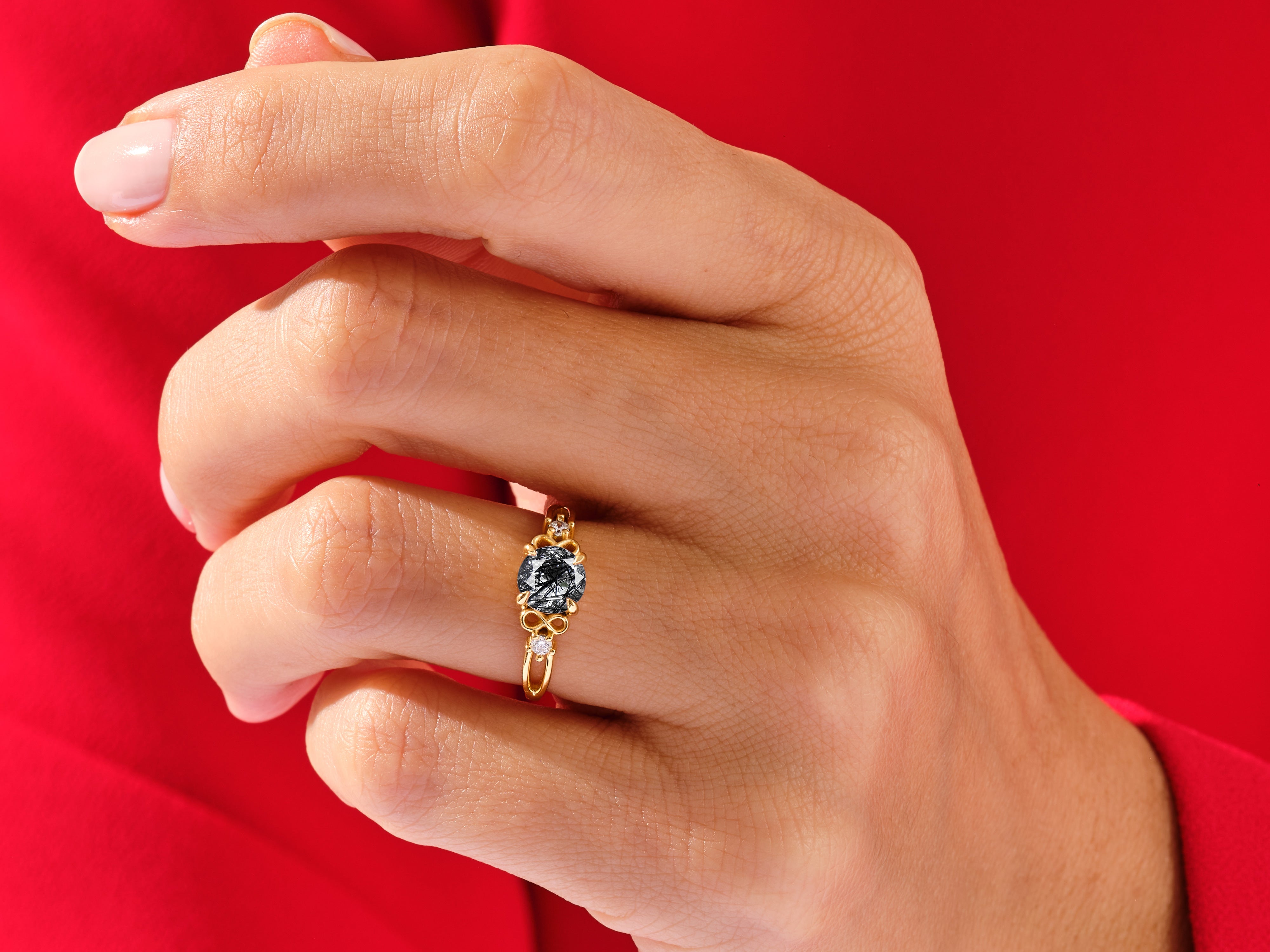 Gold ring with dark gemstone and diamonds on a hand