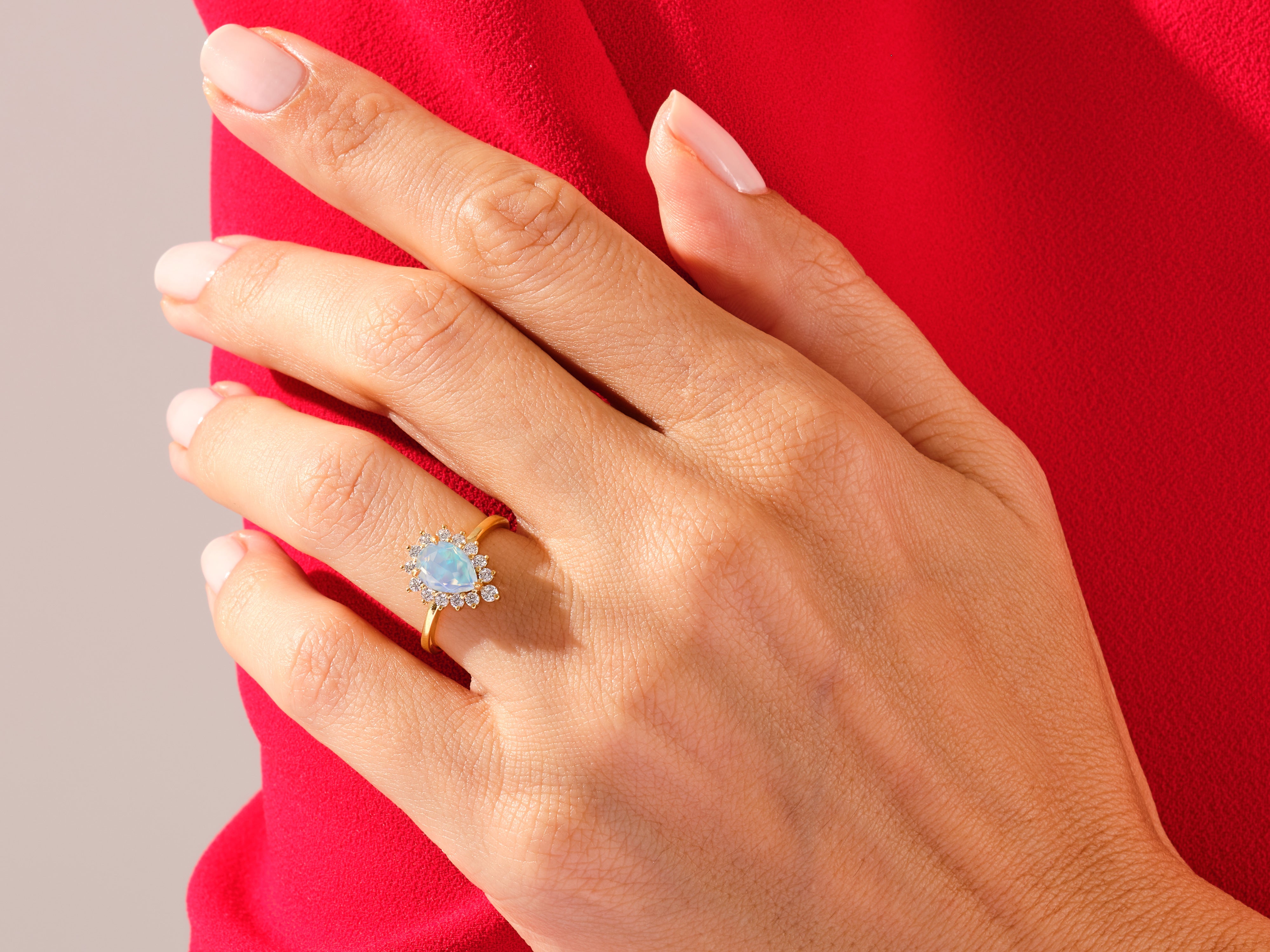Gold opal diamond halo ring on hand