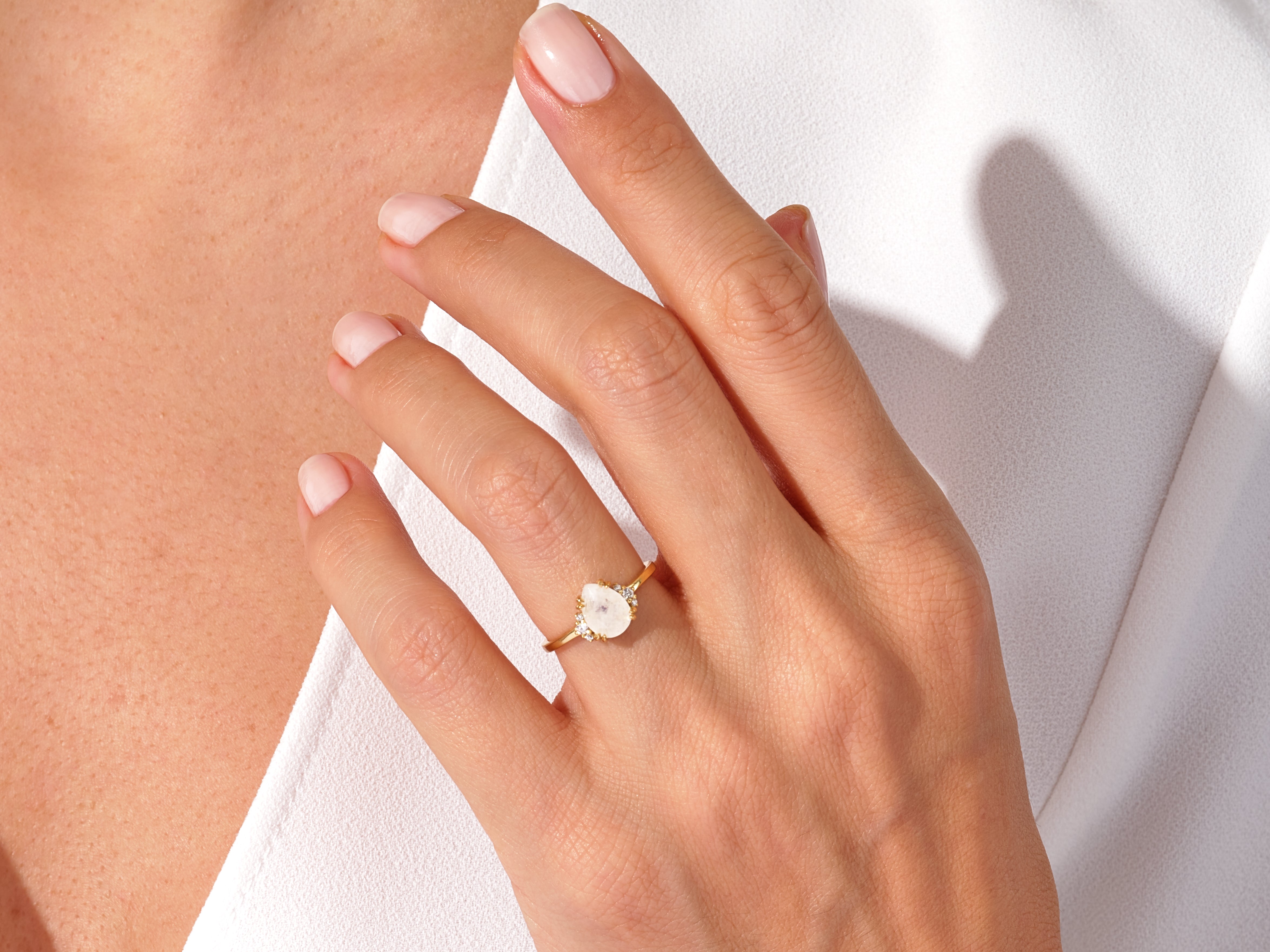 Gold ring with oval gemstone and diamonds on a woman's hand