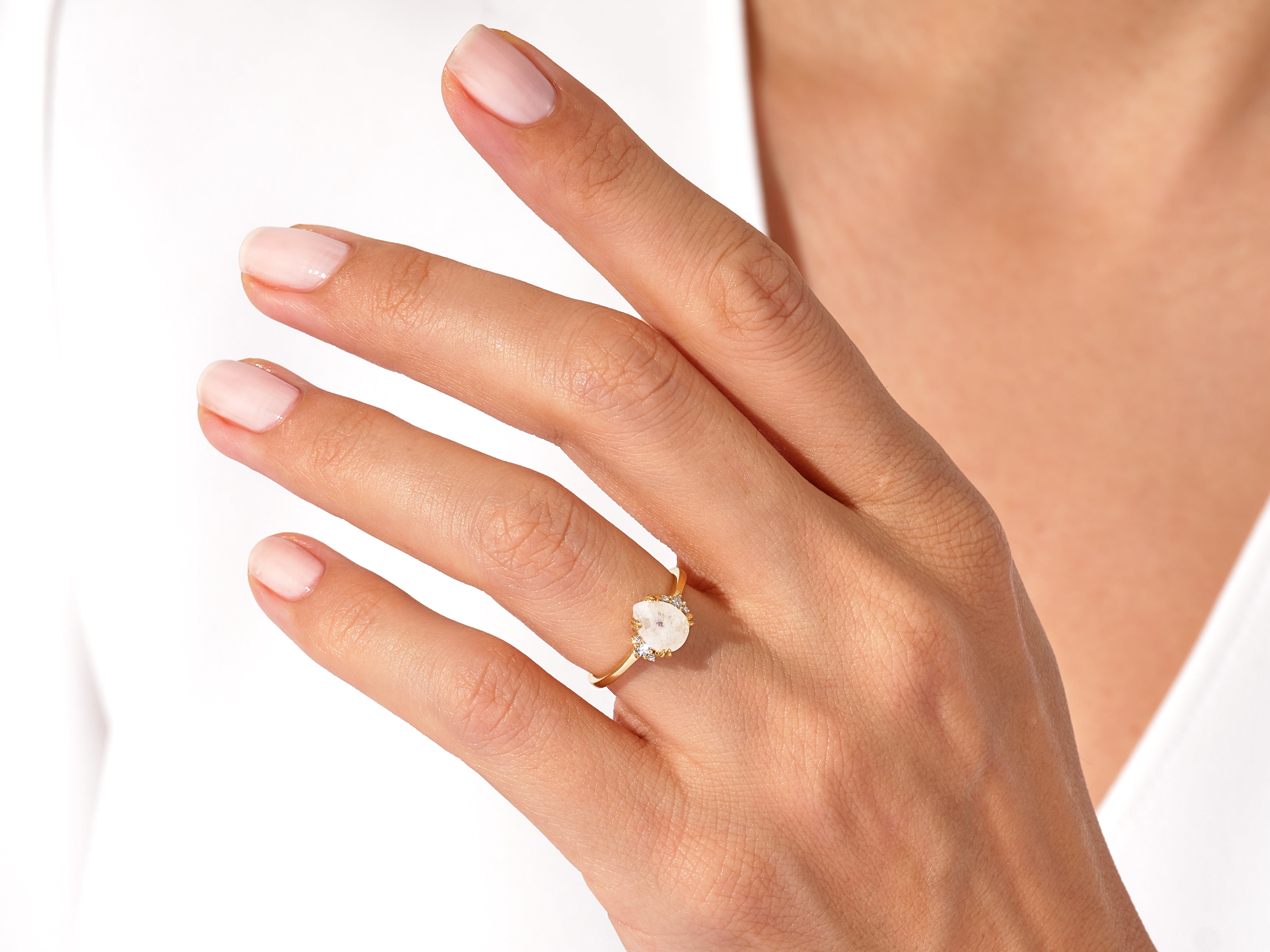 Gold ring with oval gemstone and diamonds on a woman's hand