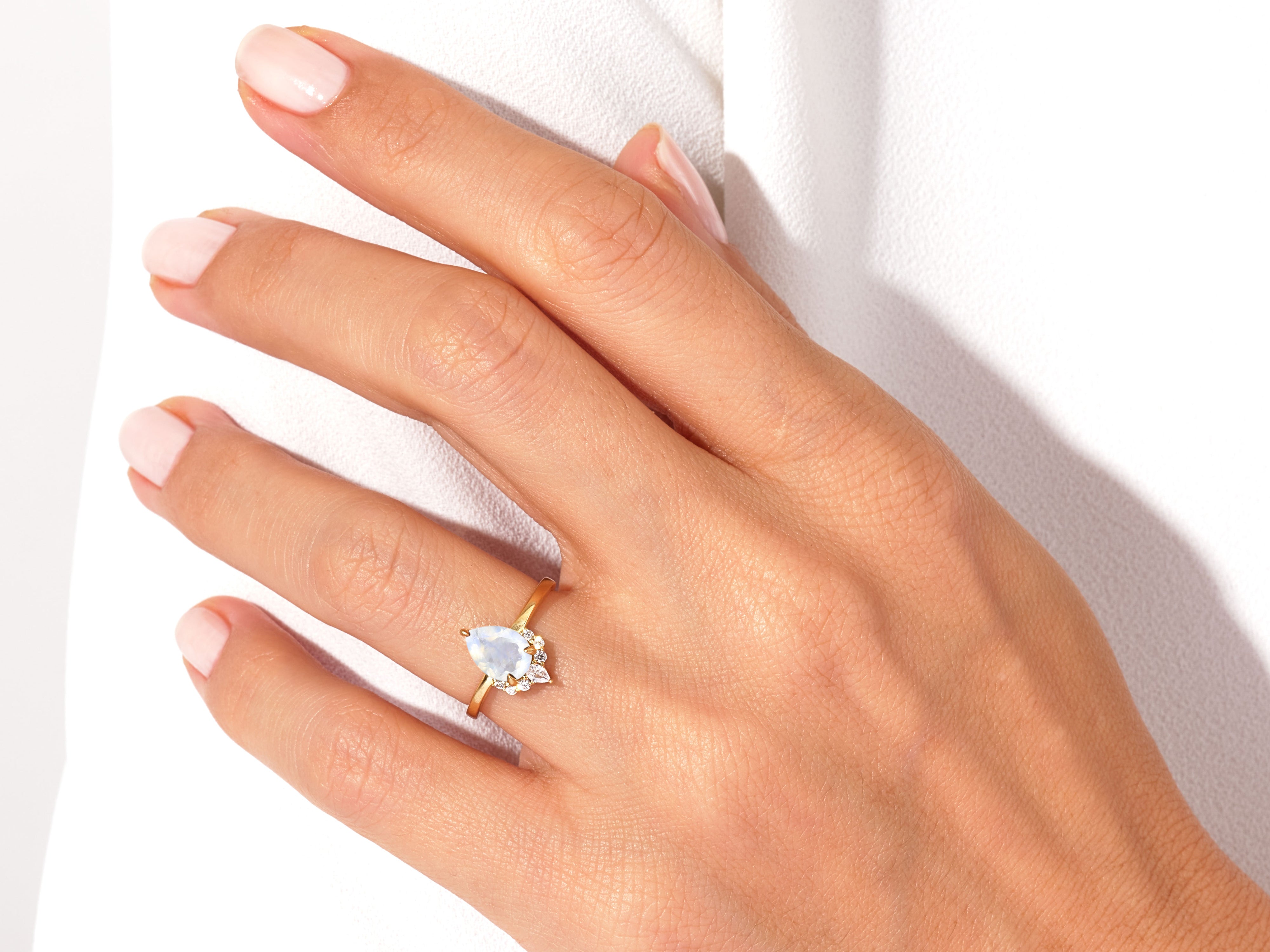 Pear-shaped moonstone ring with diamonds on a hand