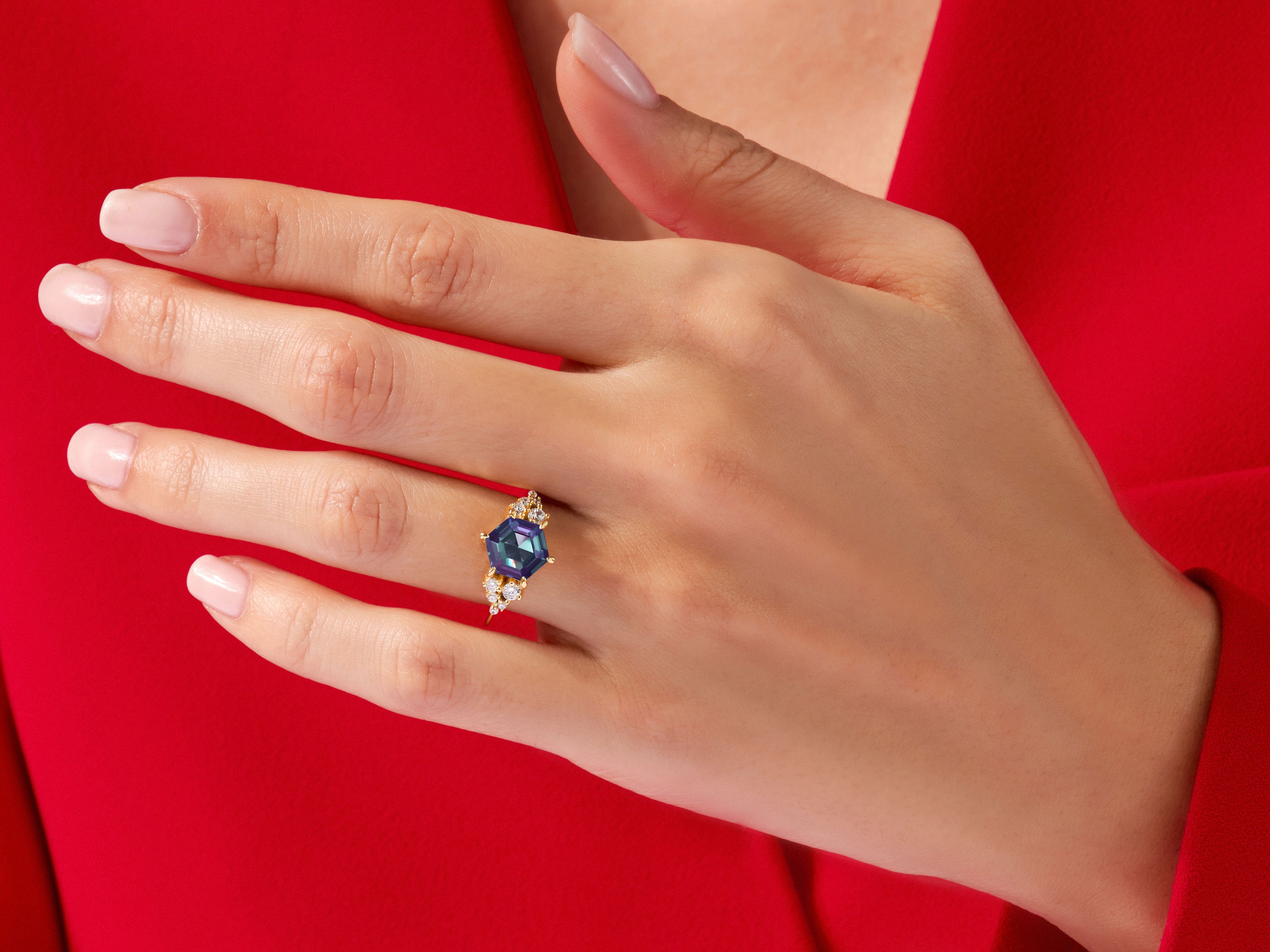 Hexagonal gemstone ring with diamonds on a red background