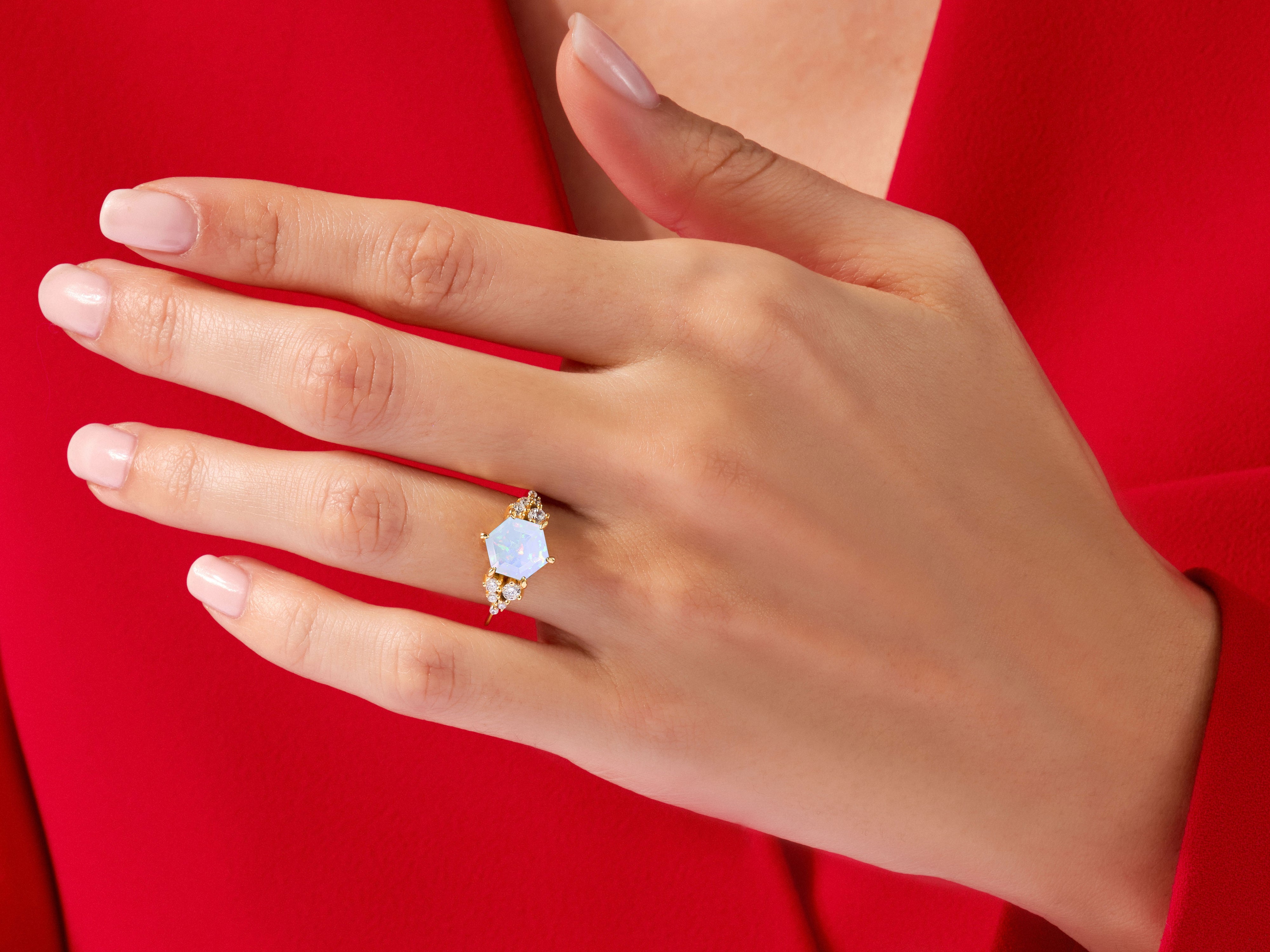 Hexagonal opal and diamond ring on a hand