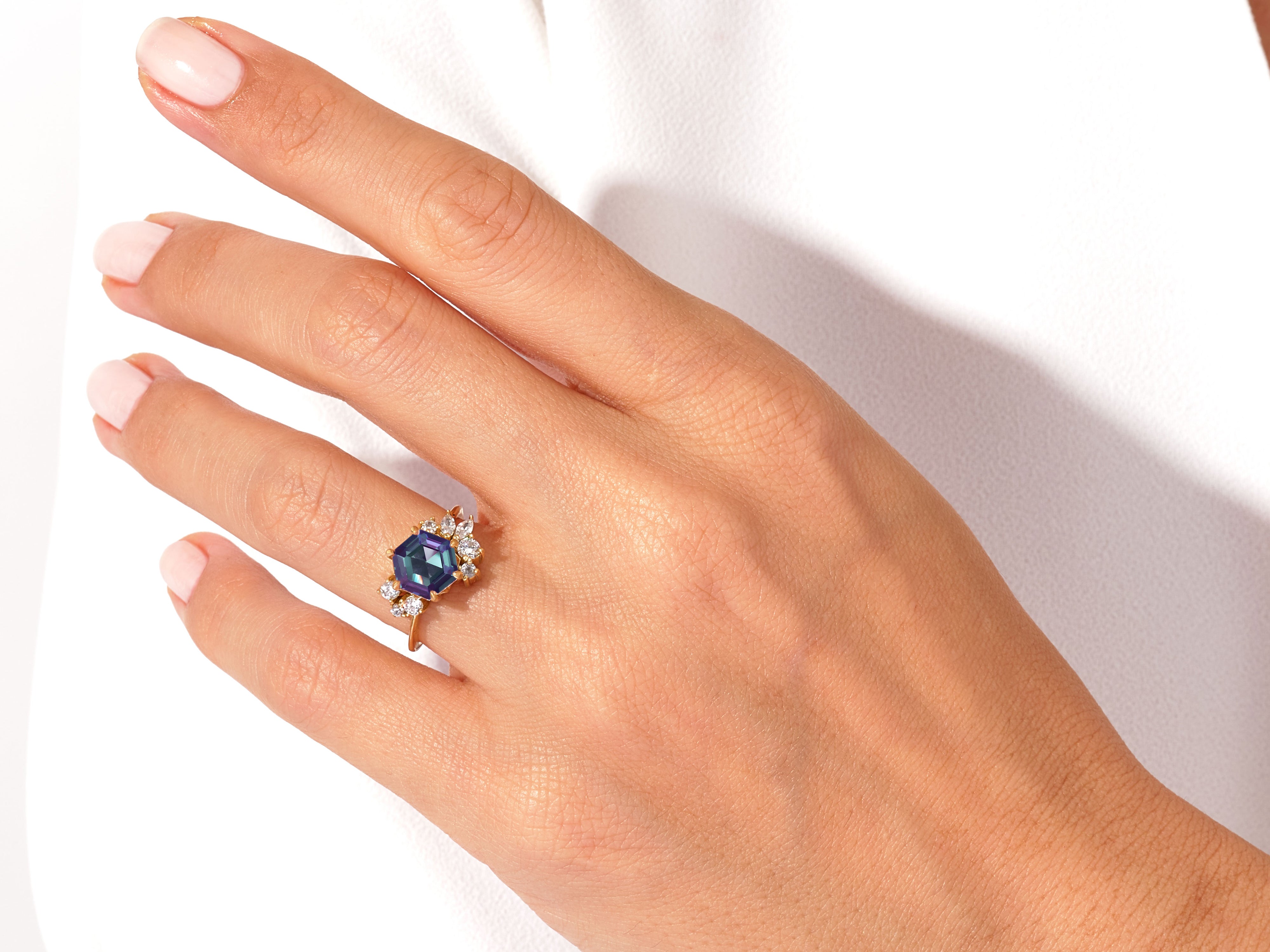 Hexagonal gemstone ring with diamonds on a woman's hand