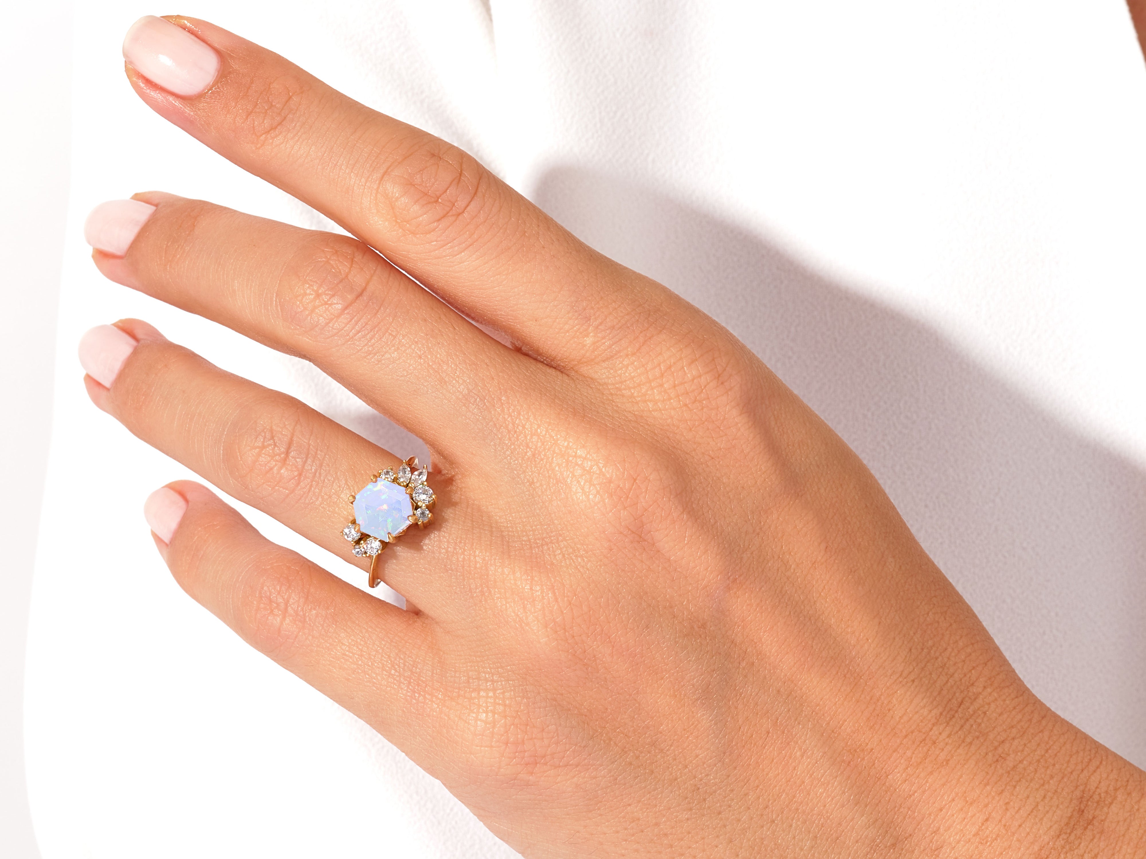 Gold opal ring with diamonds on a hand