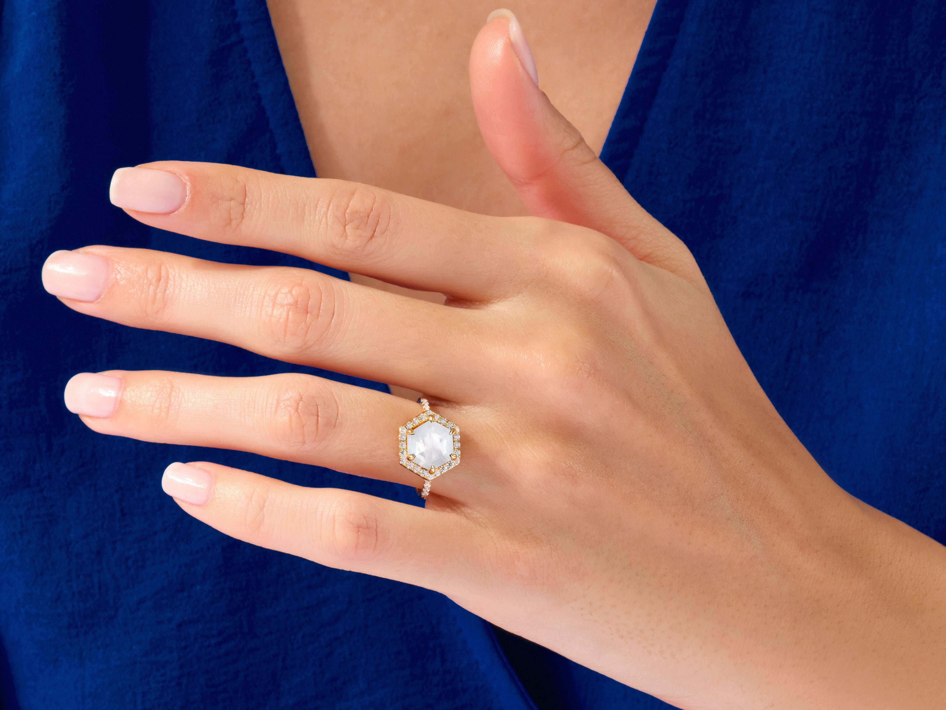 Hexagonal diamond engagement ring with gold band on hand