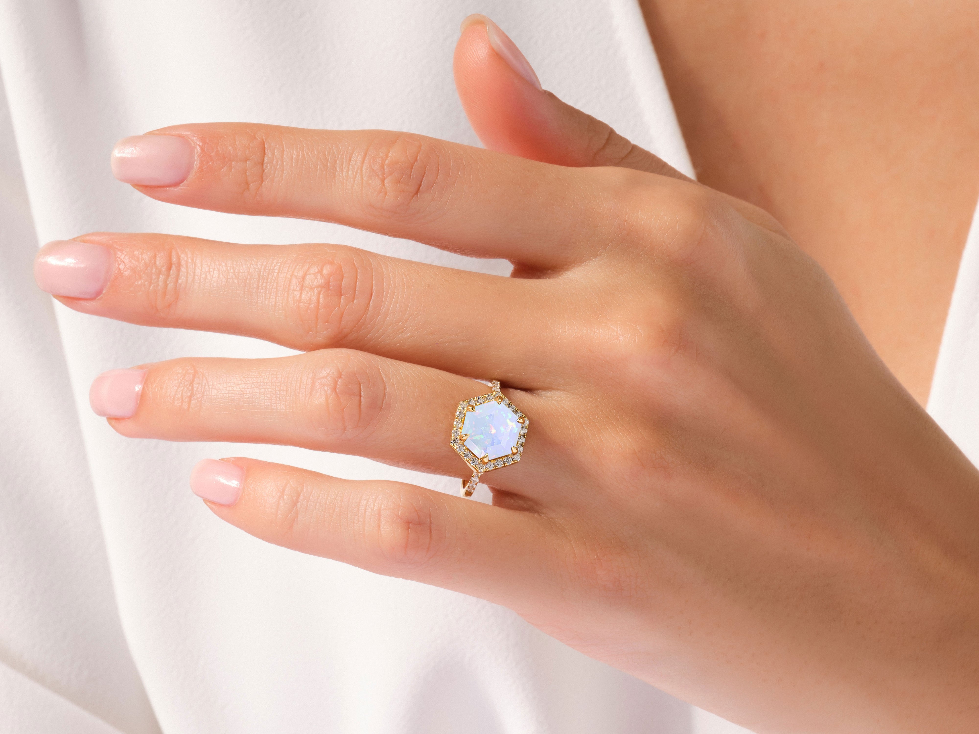 Hexagonal opal and diamond ring on a woman's hand