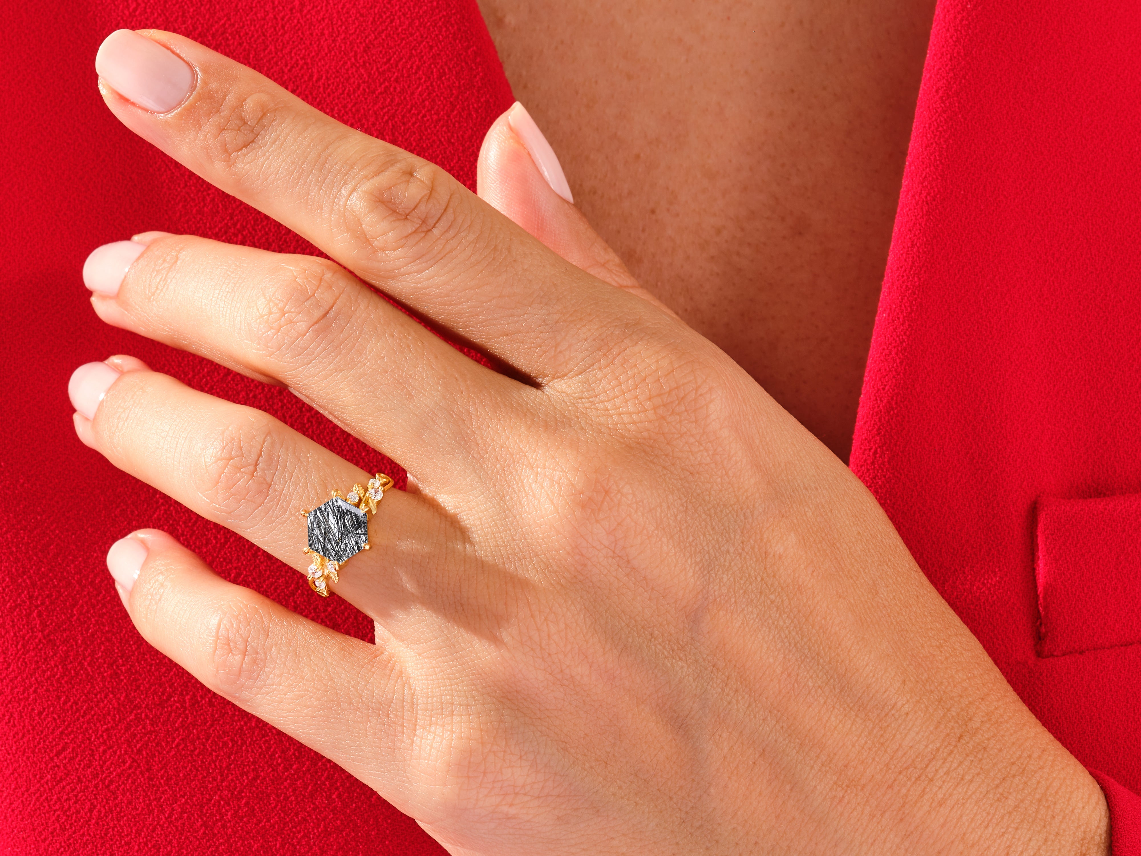 Gold ring with black gemstone and diamonds on a hand