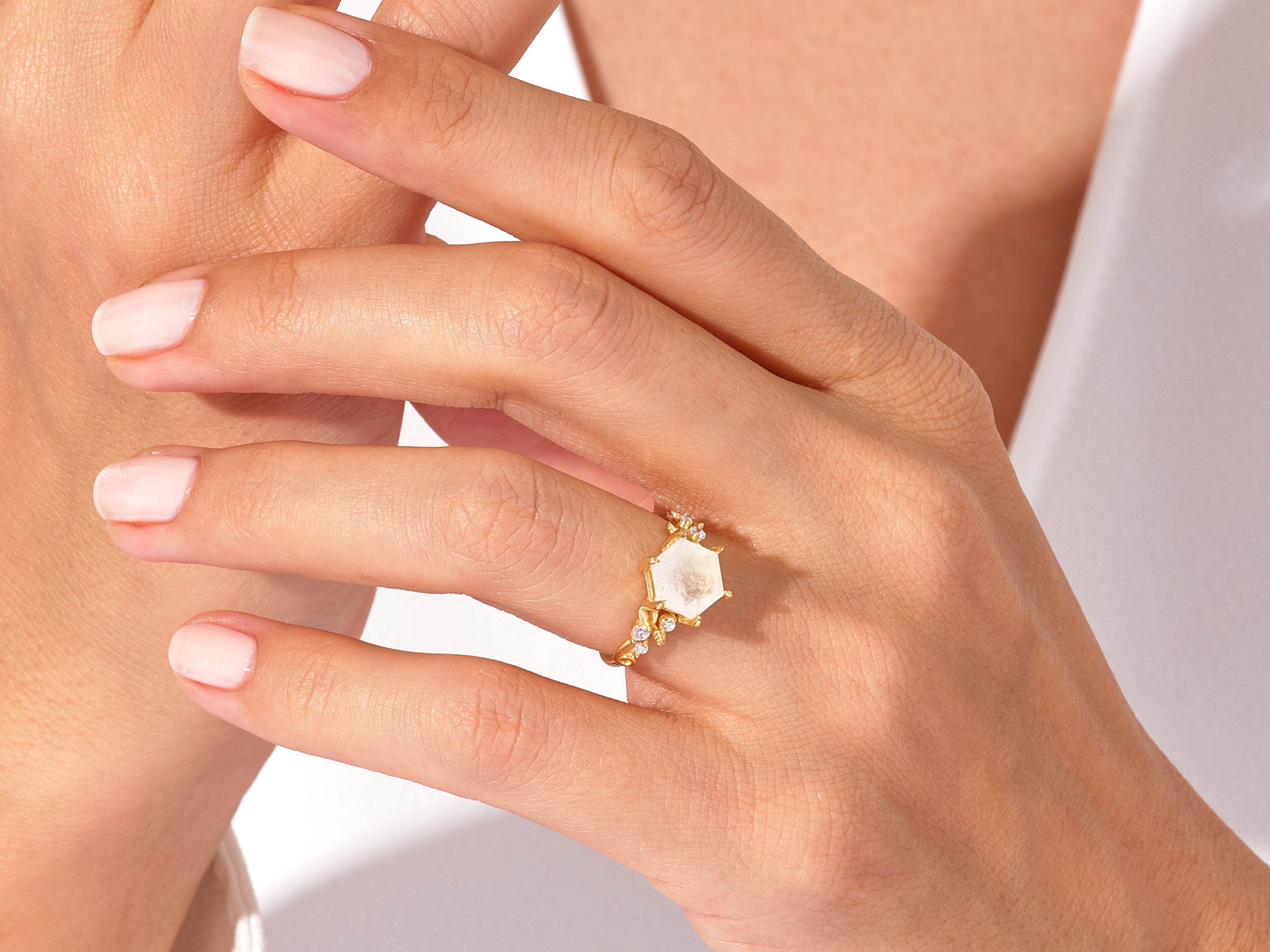 Hexagonal gemstone ring with diamonds on a woman's hand