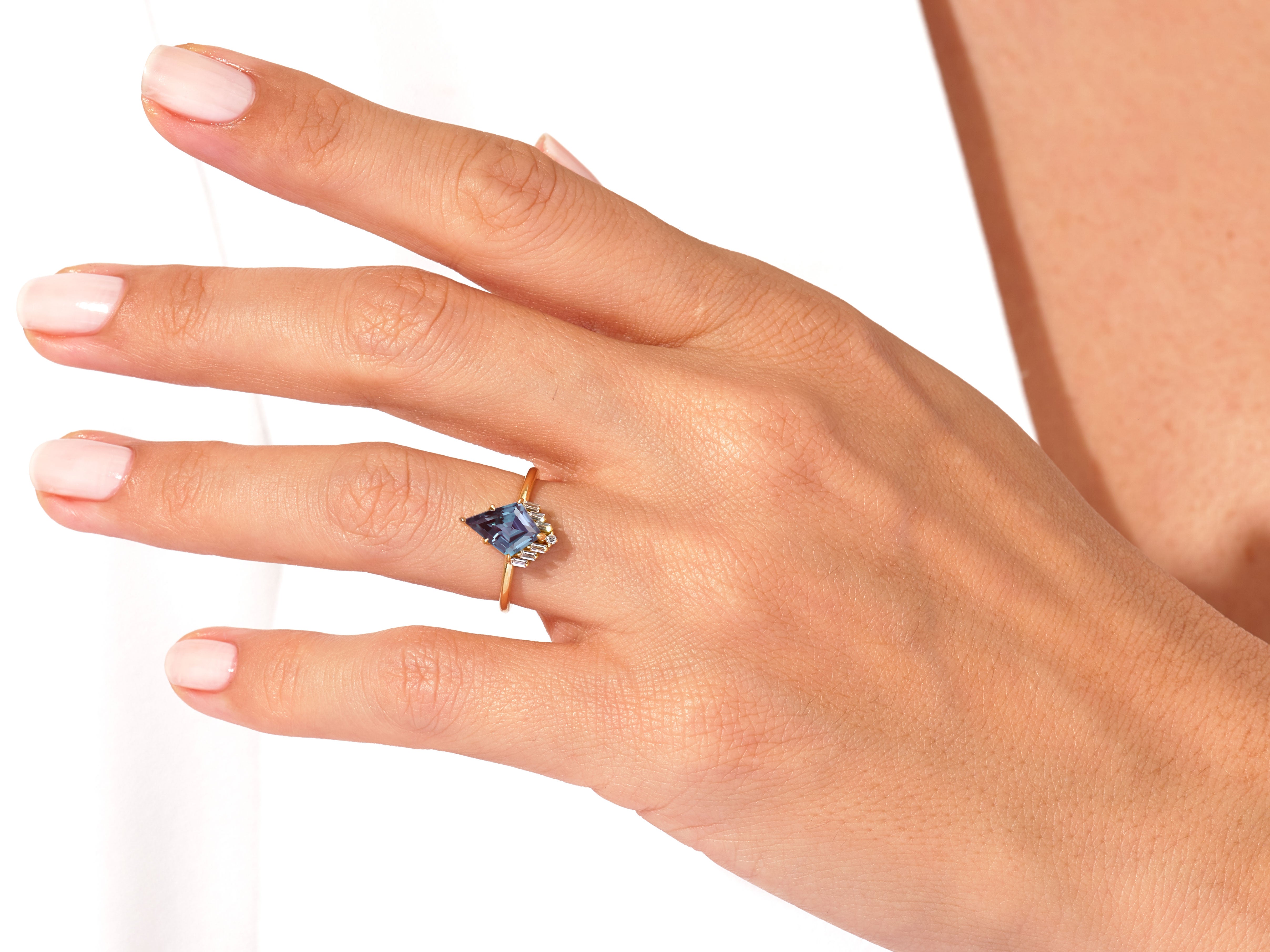 Jewelry: Kite-shaped blue gemstone ring with diamonds on gold band
