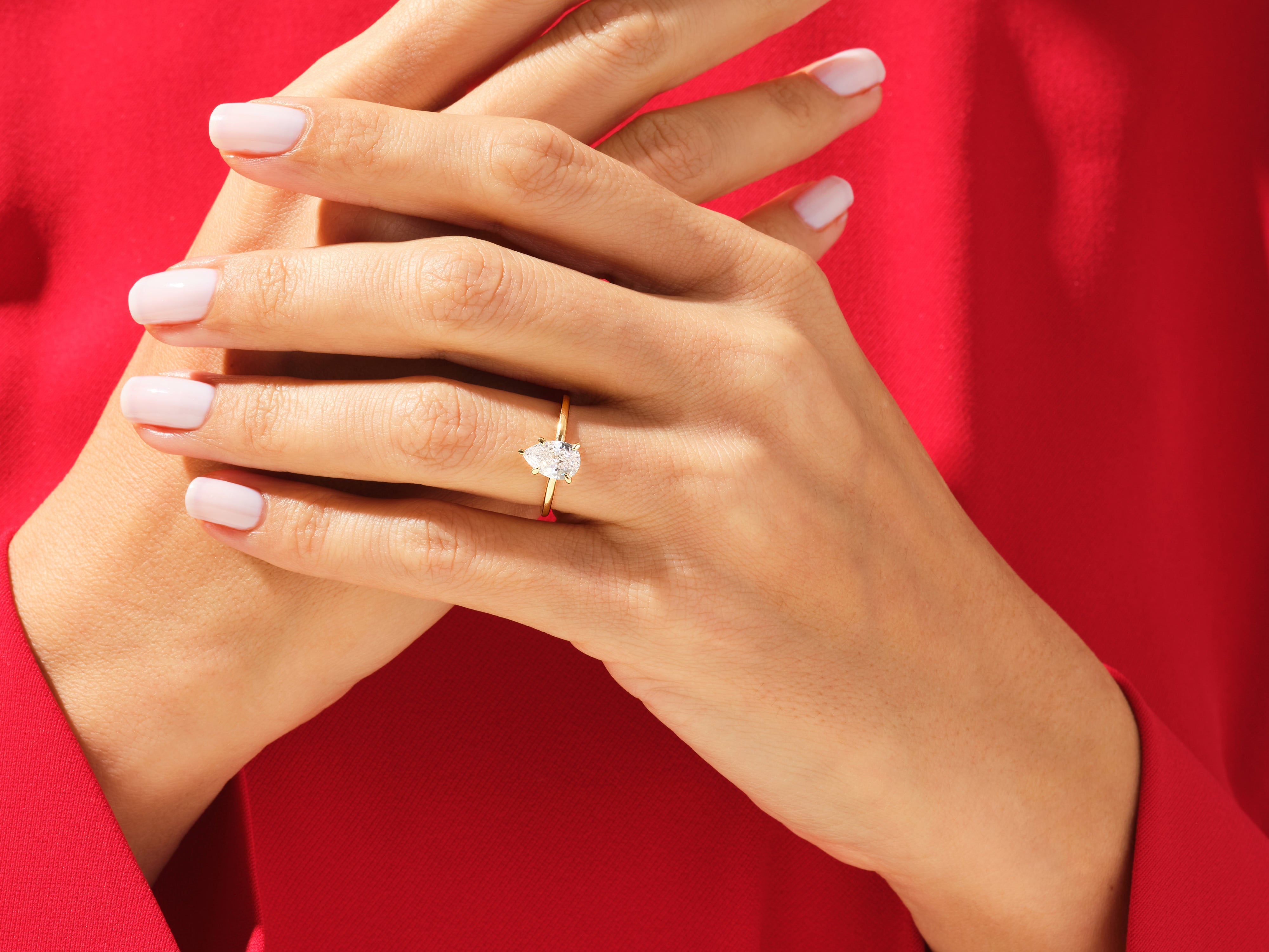 Pear-shaped diamond engagement ring on a hand, jewelry