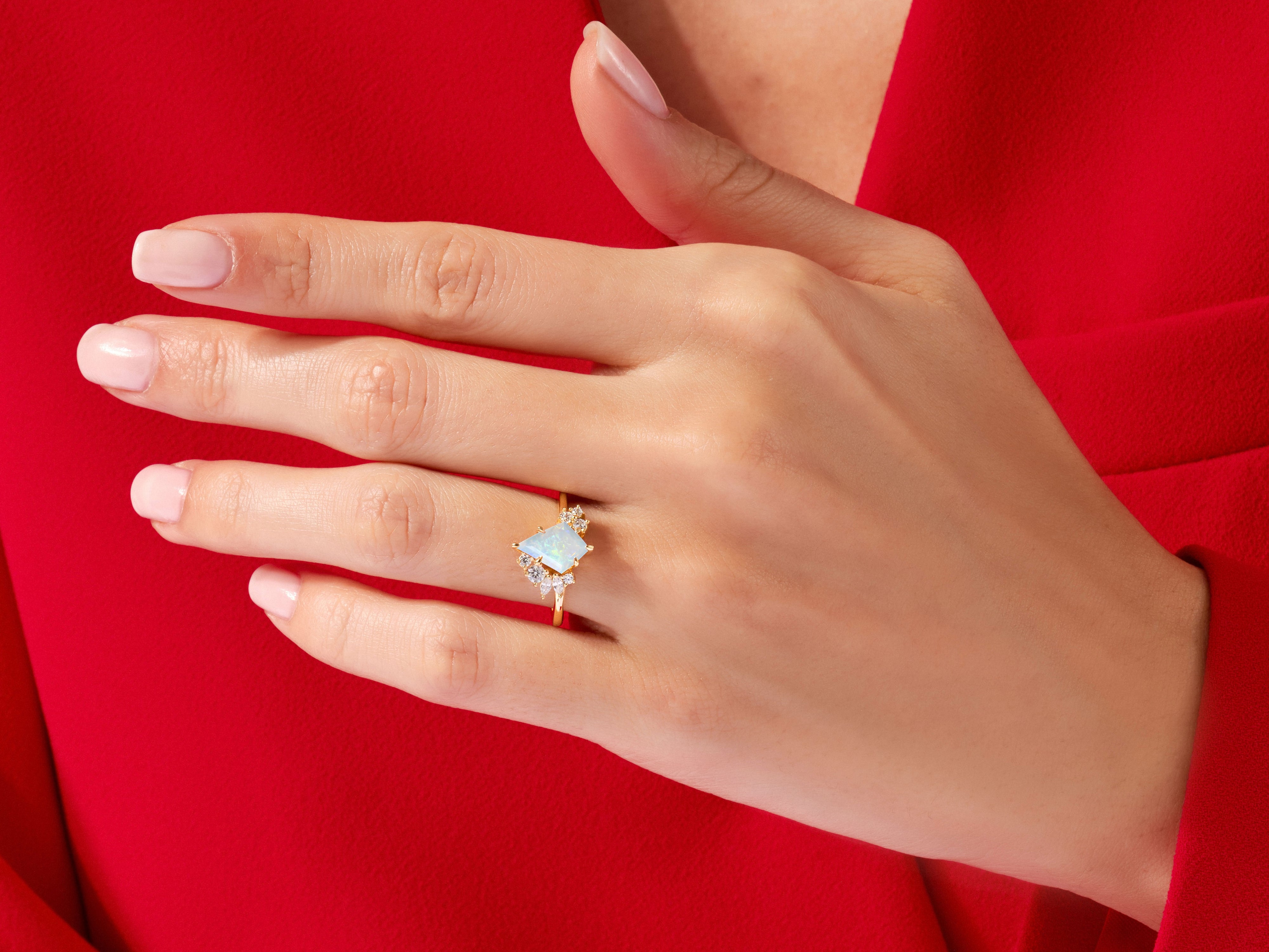 Gold opal ring with diamonds on a red background