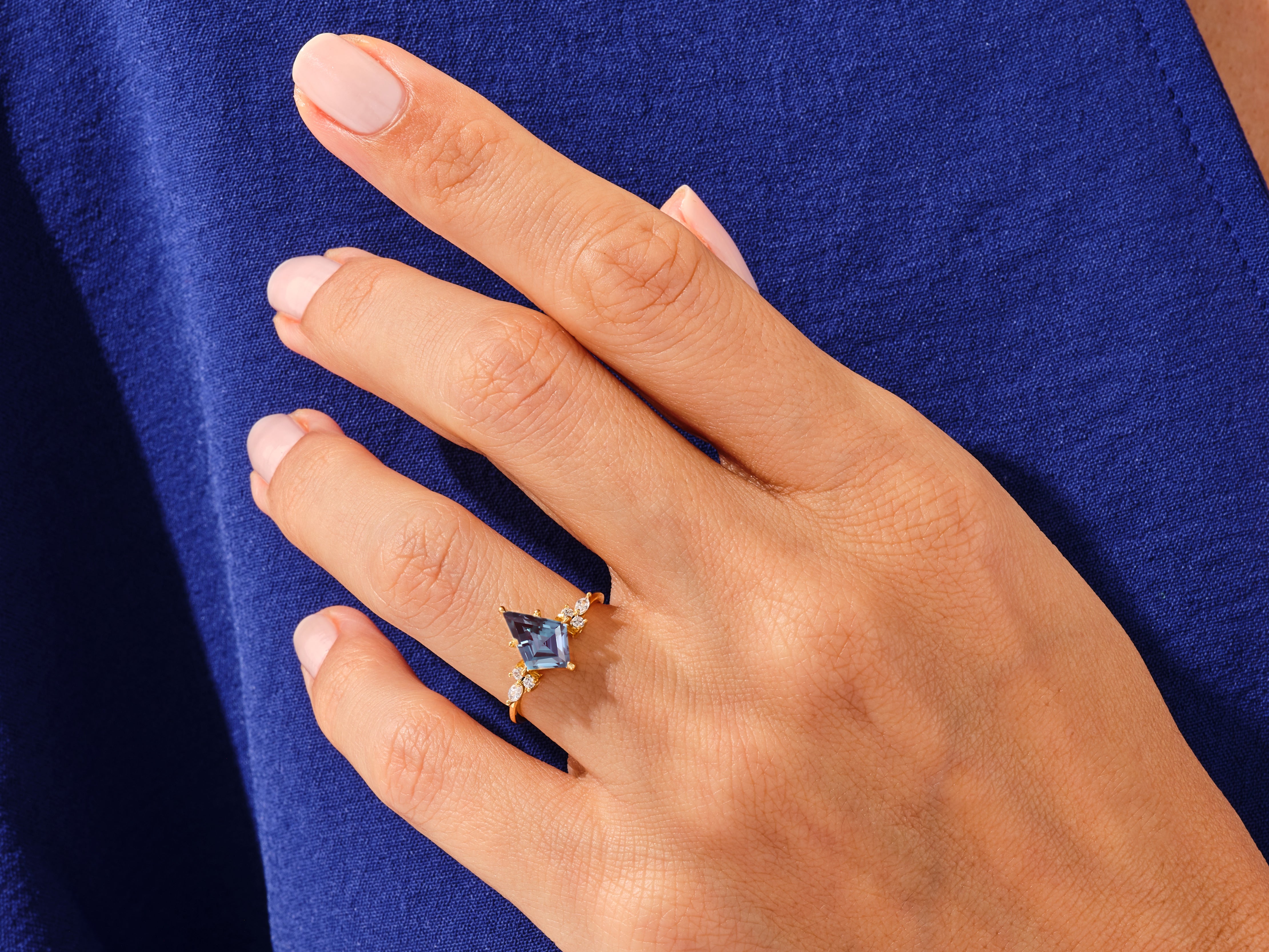 Gold ring with blue gemstone and diamonds on a hand