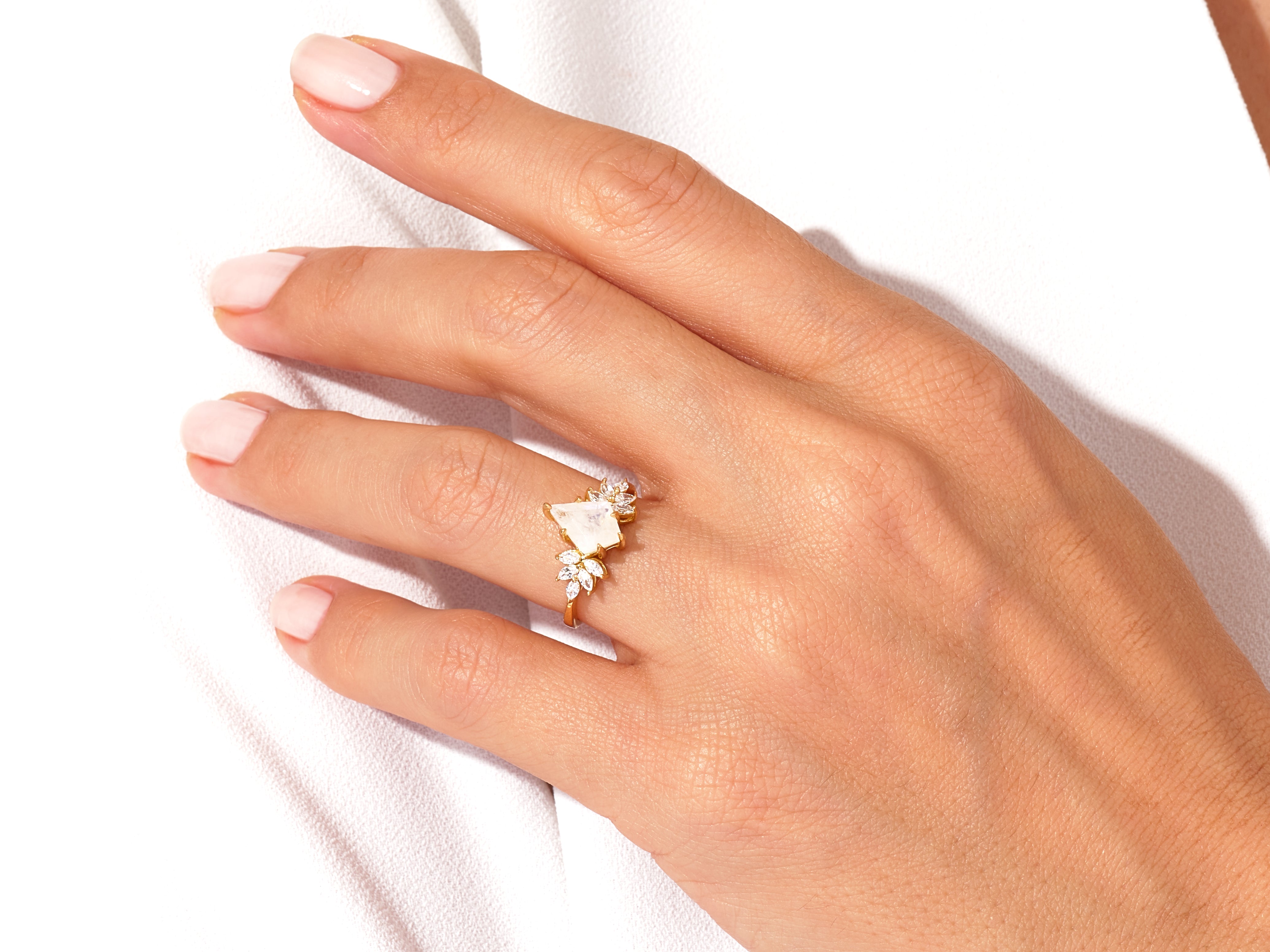 Gold ring with moonstone and diamond accents on a hand