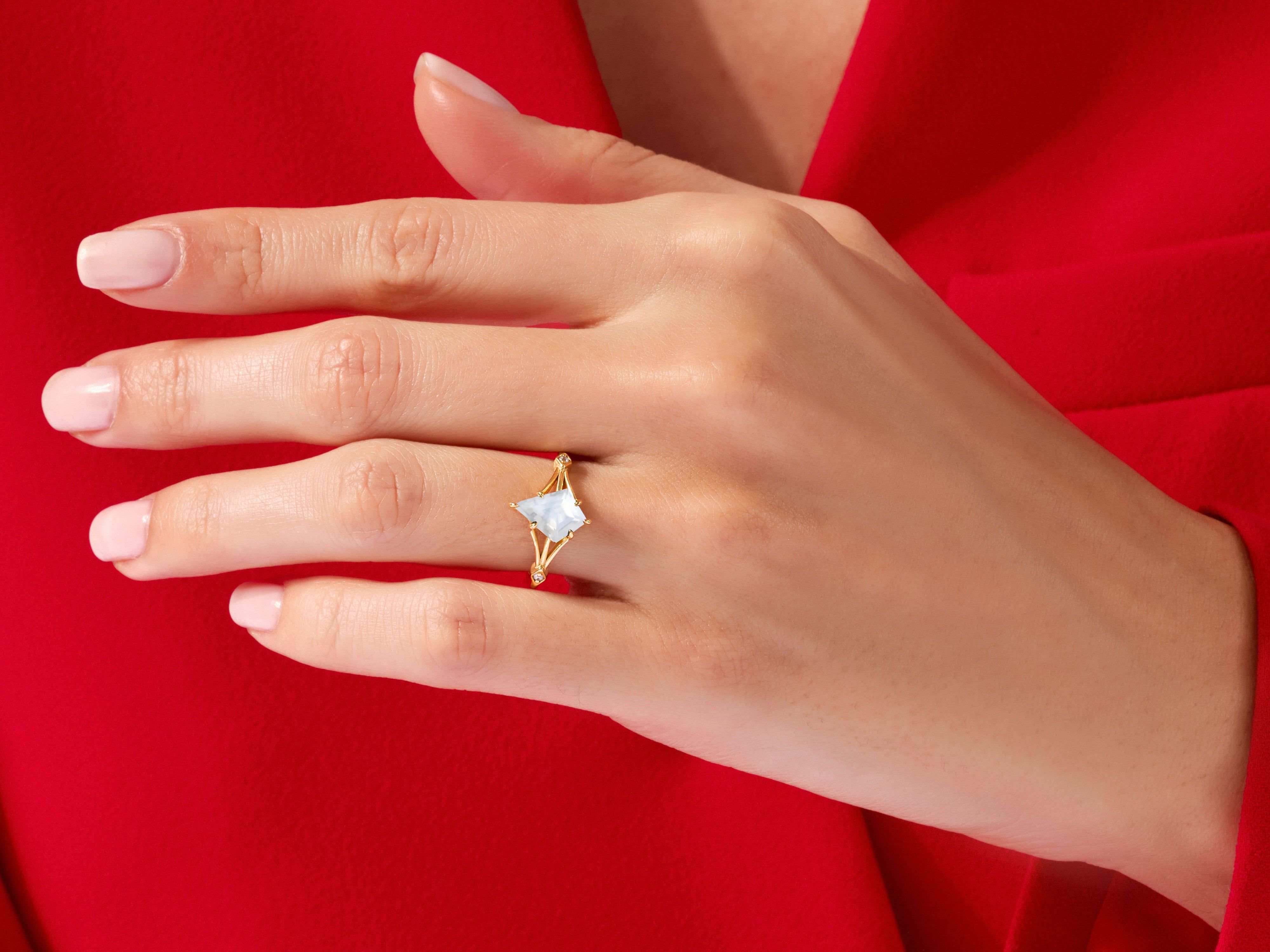 Gold ring with light blue gemstone on a woman's hand