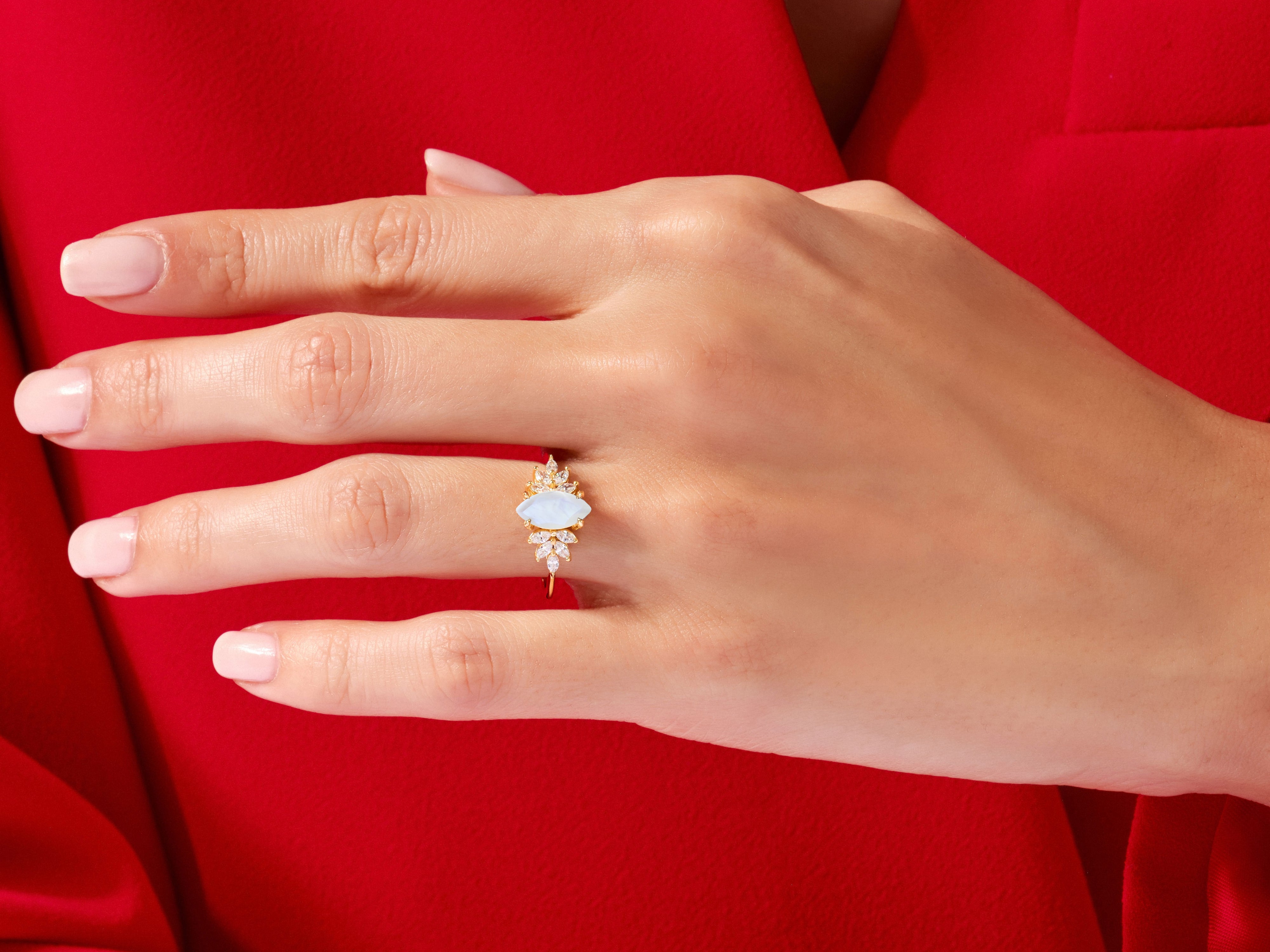 Gold marquise opal ring with diamonds on a red background