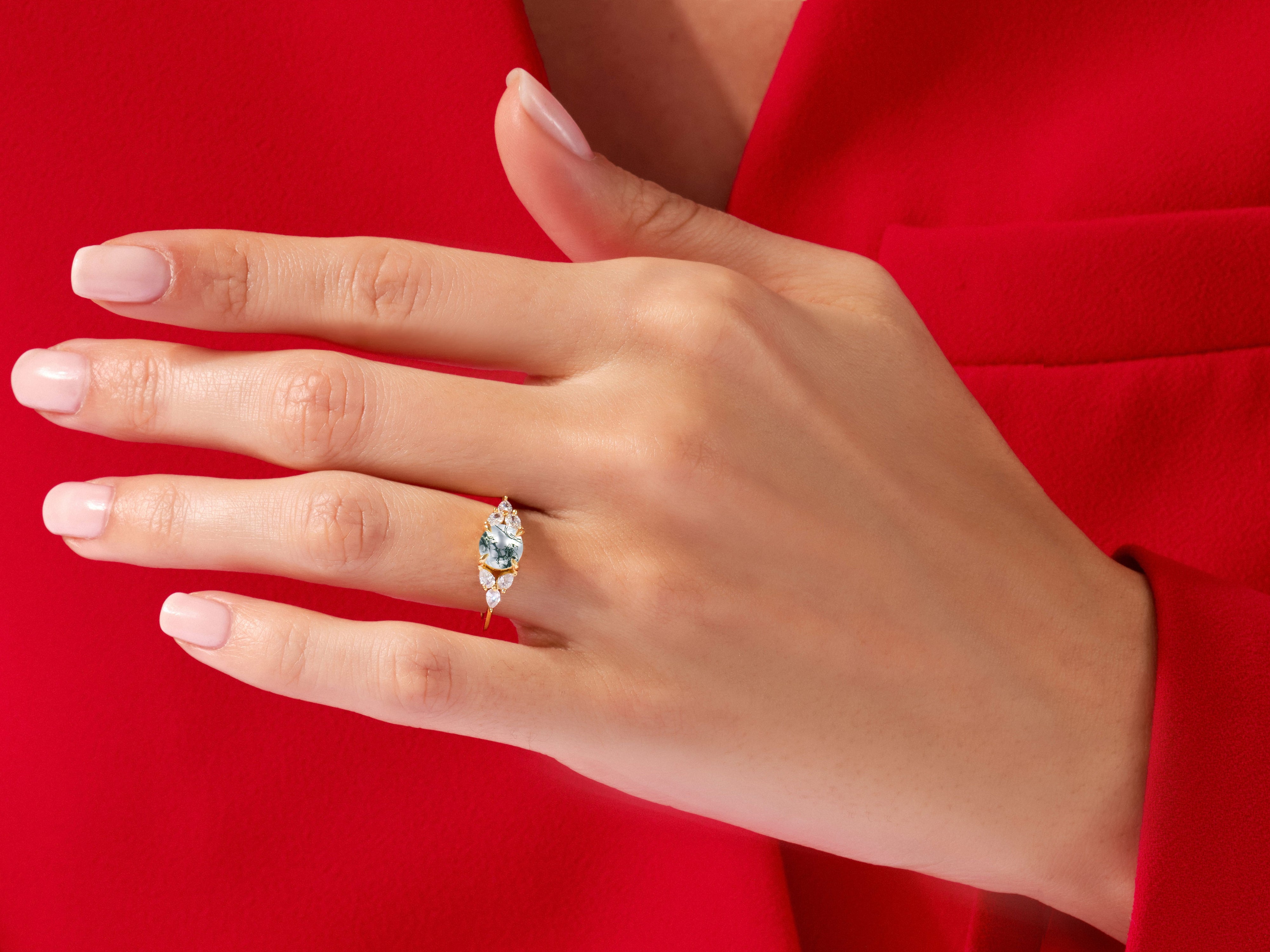 Gold ring with oval moss agate and diamond accents on hand