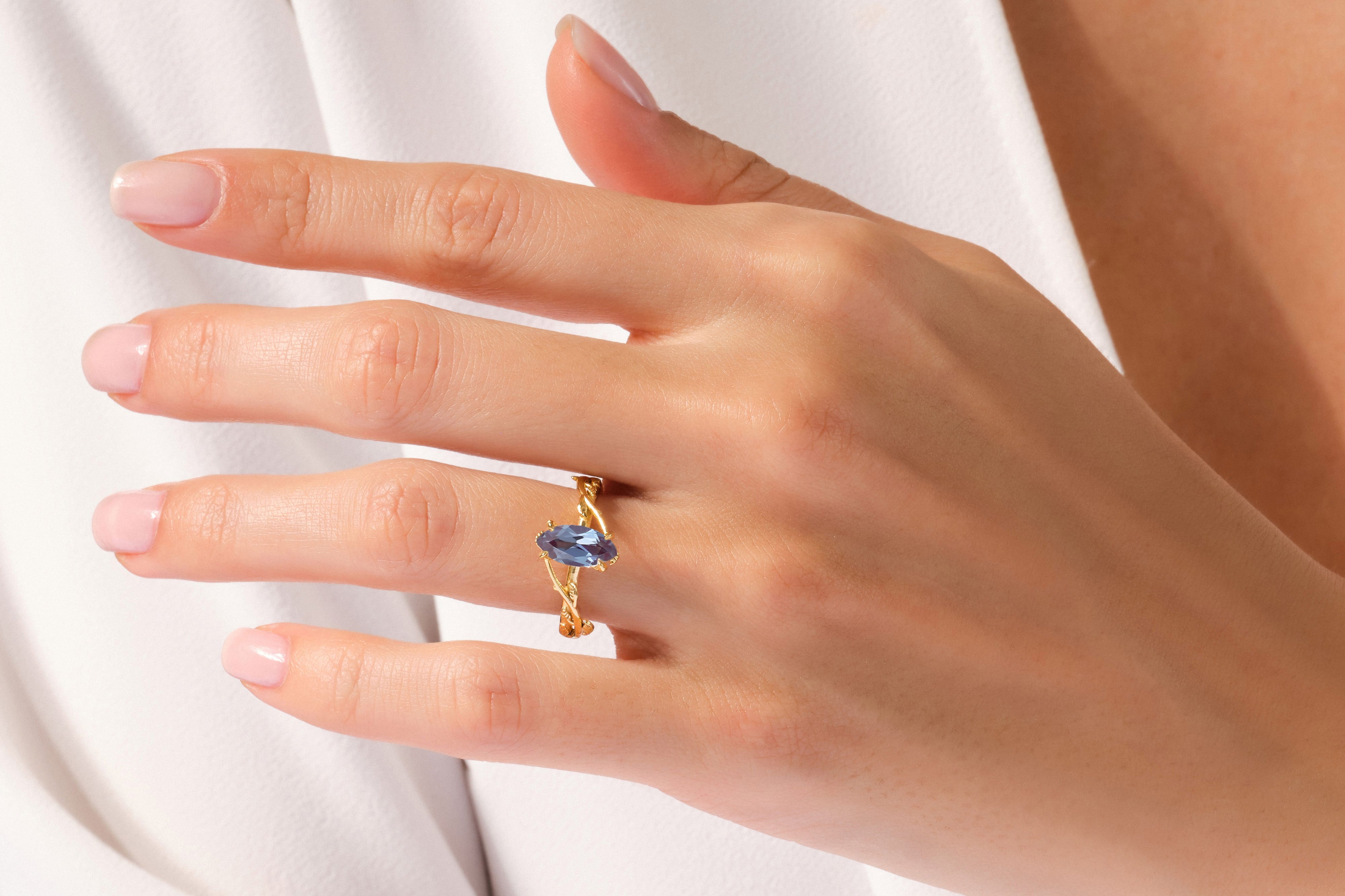 Gold ring with blue marquise gemstone on a woman's finger