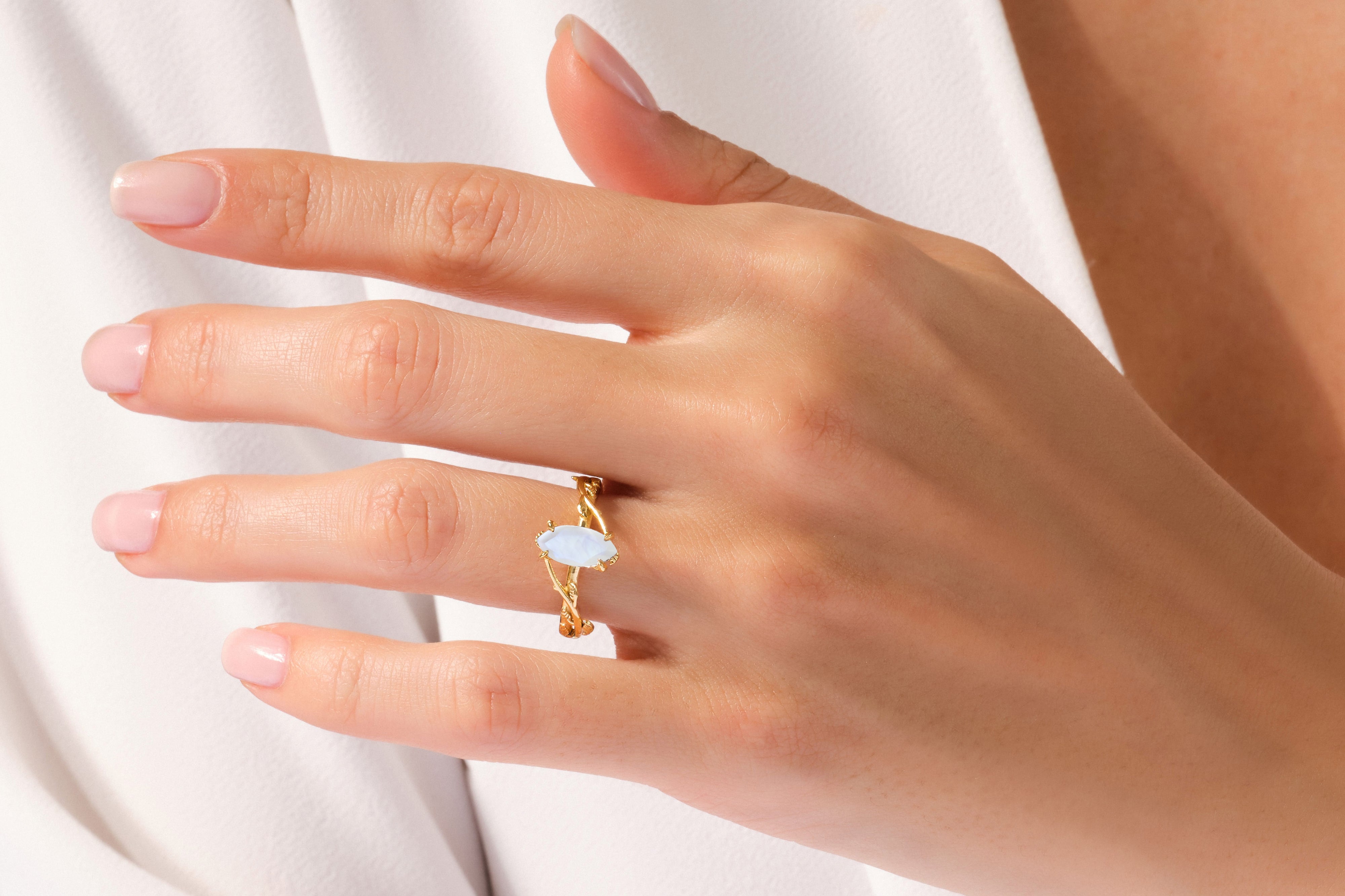 Gold ring with oval blue gemstone on a woman's finger