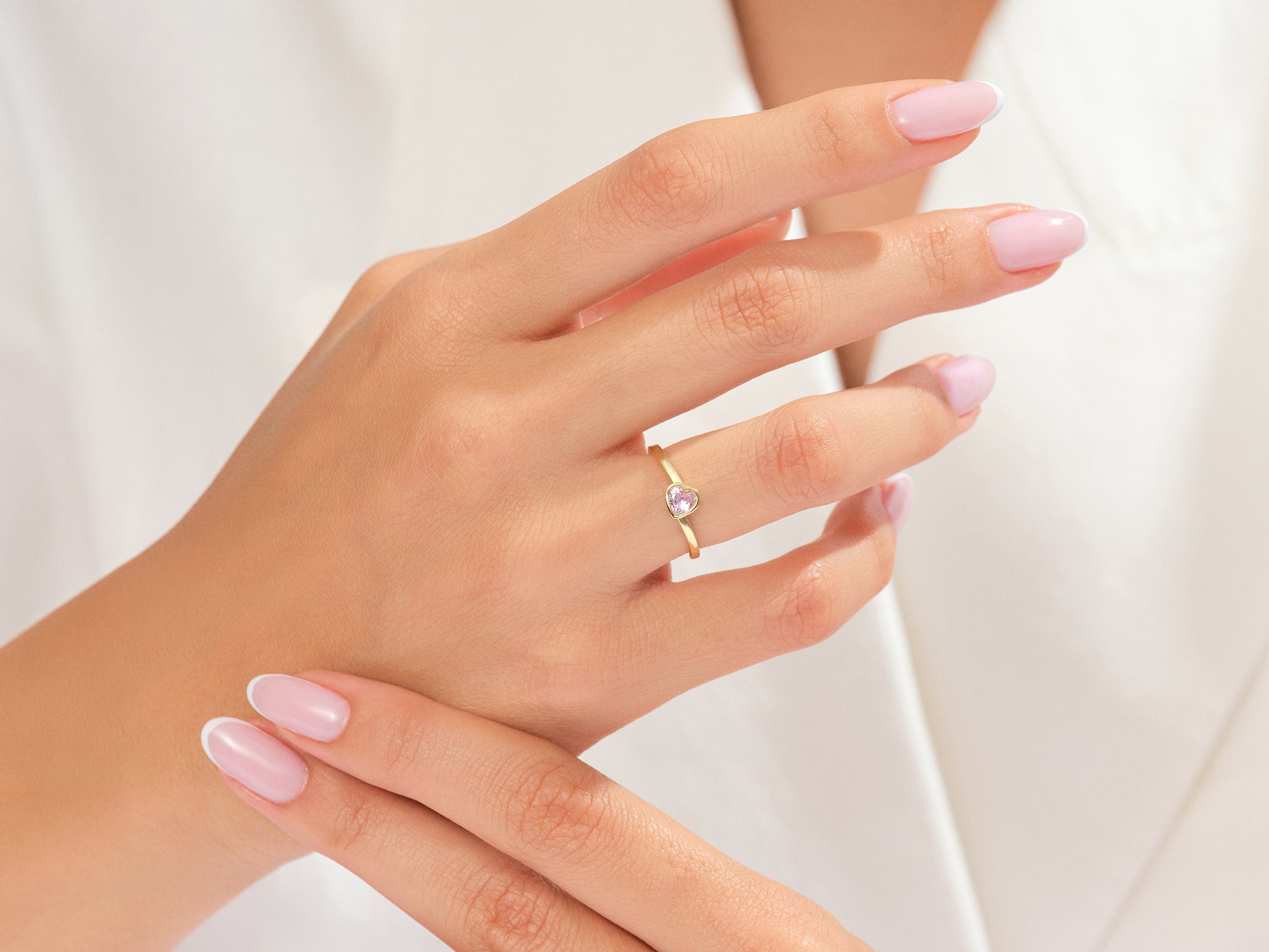 Gold ring with pink heart gemstone on a woman's hand