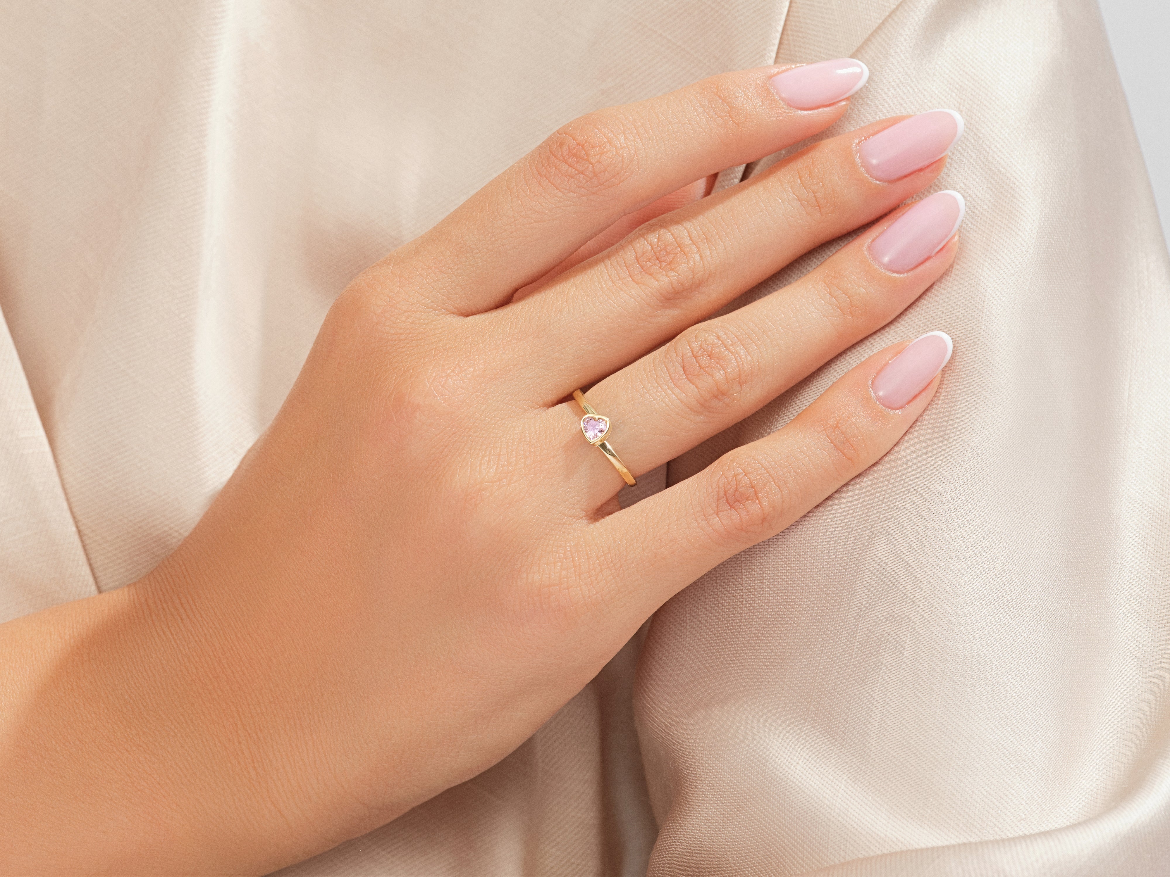 Gold ring with pink heart gemstone on a woman's hand