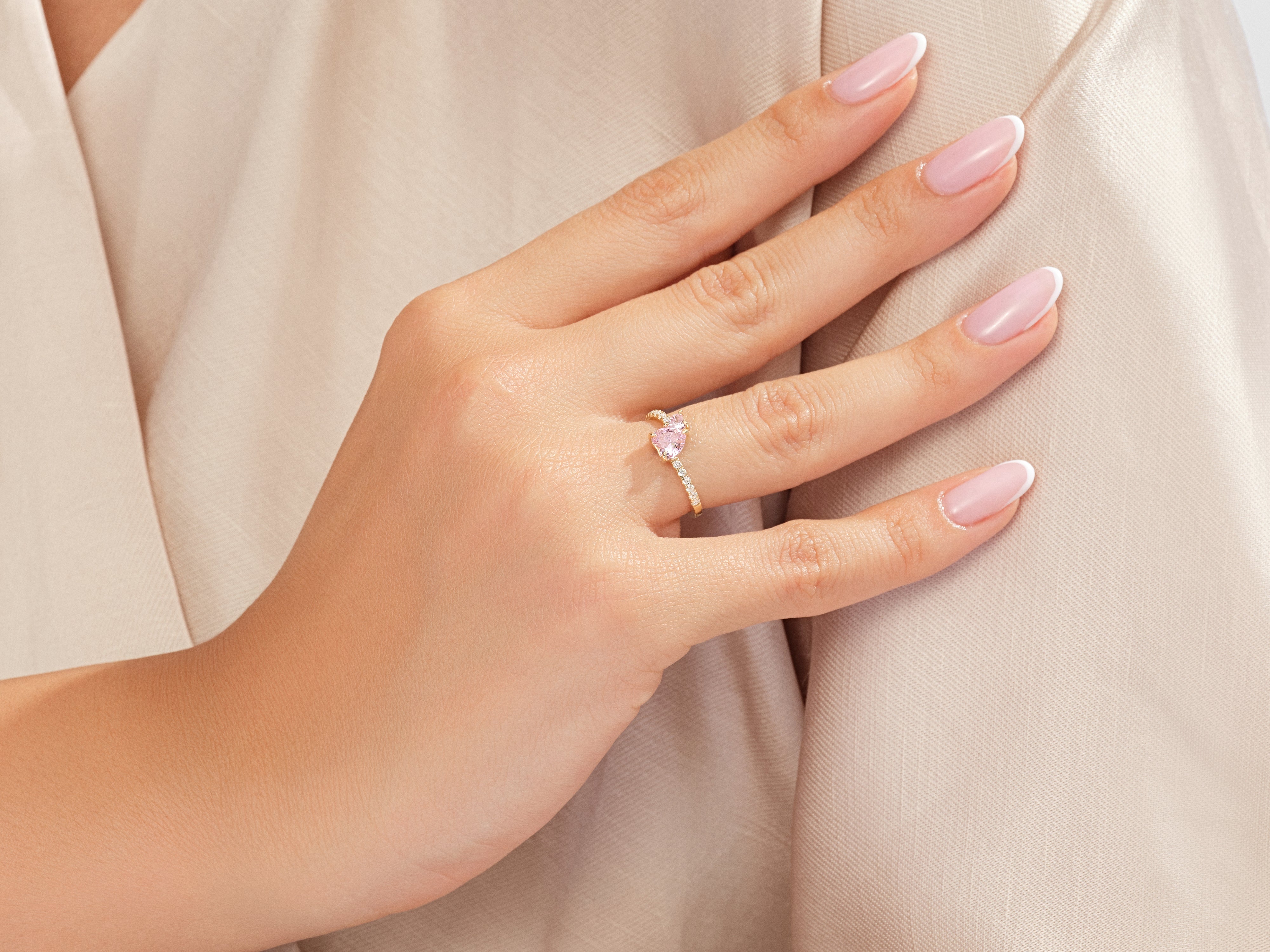 Gold heart ring with pink stone and diamonds on a woman's hand