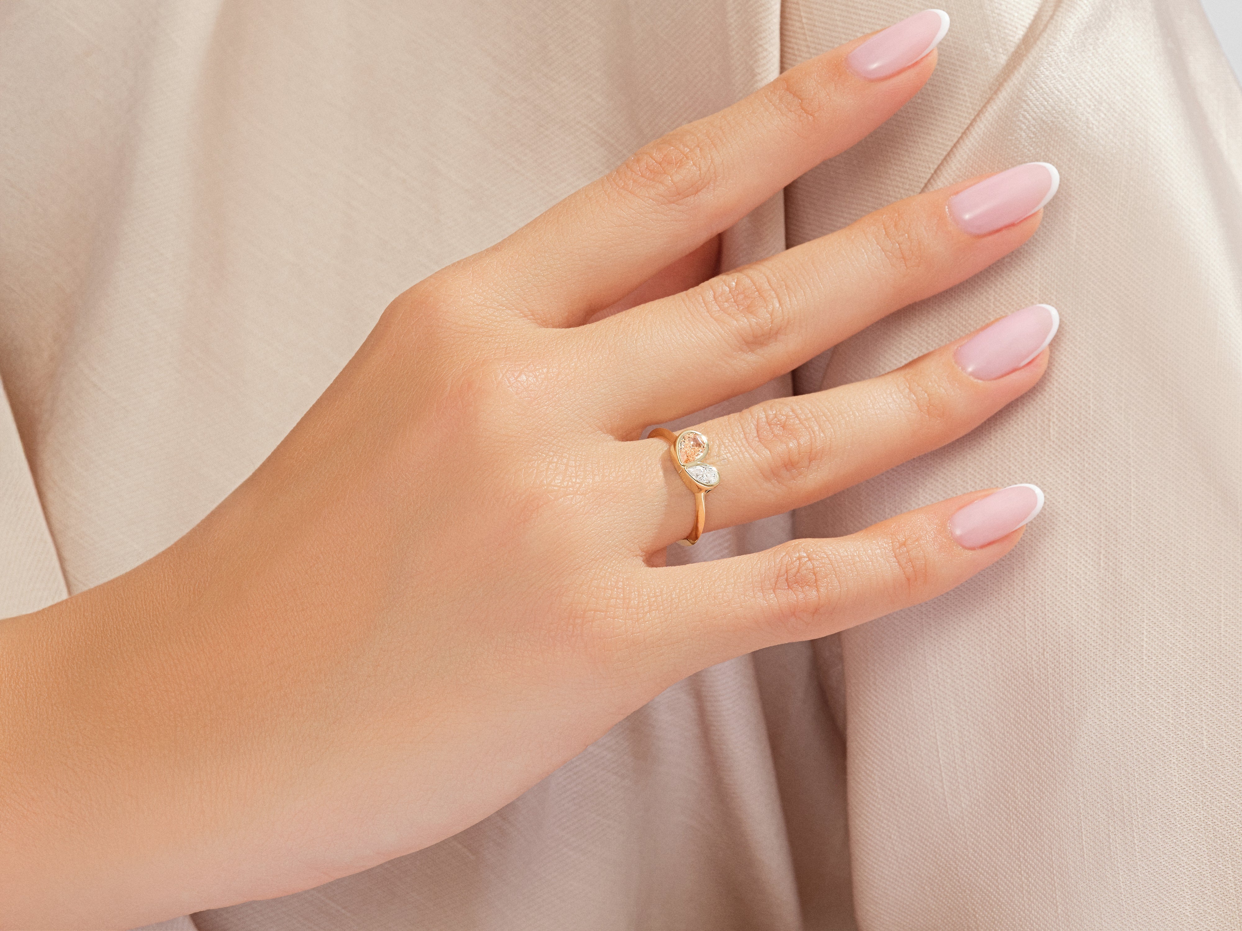 Gold ring with peach and diamond stones on a hand
