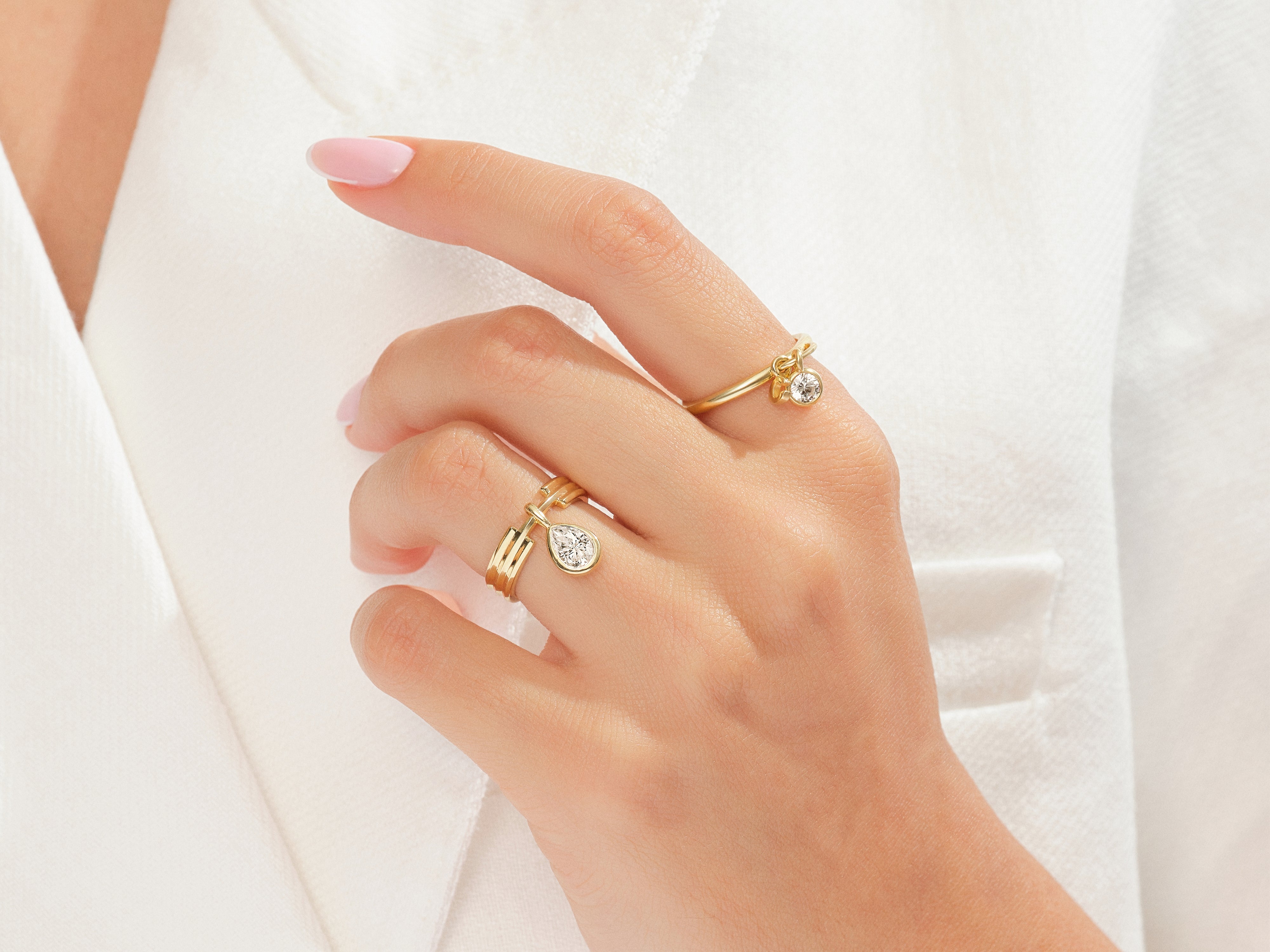 Gold rings with diamond charms on a hand