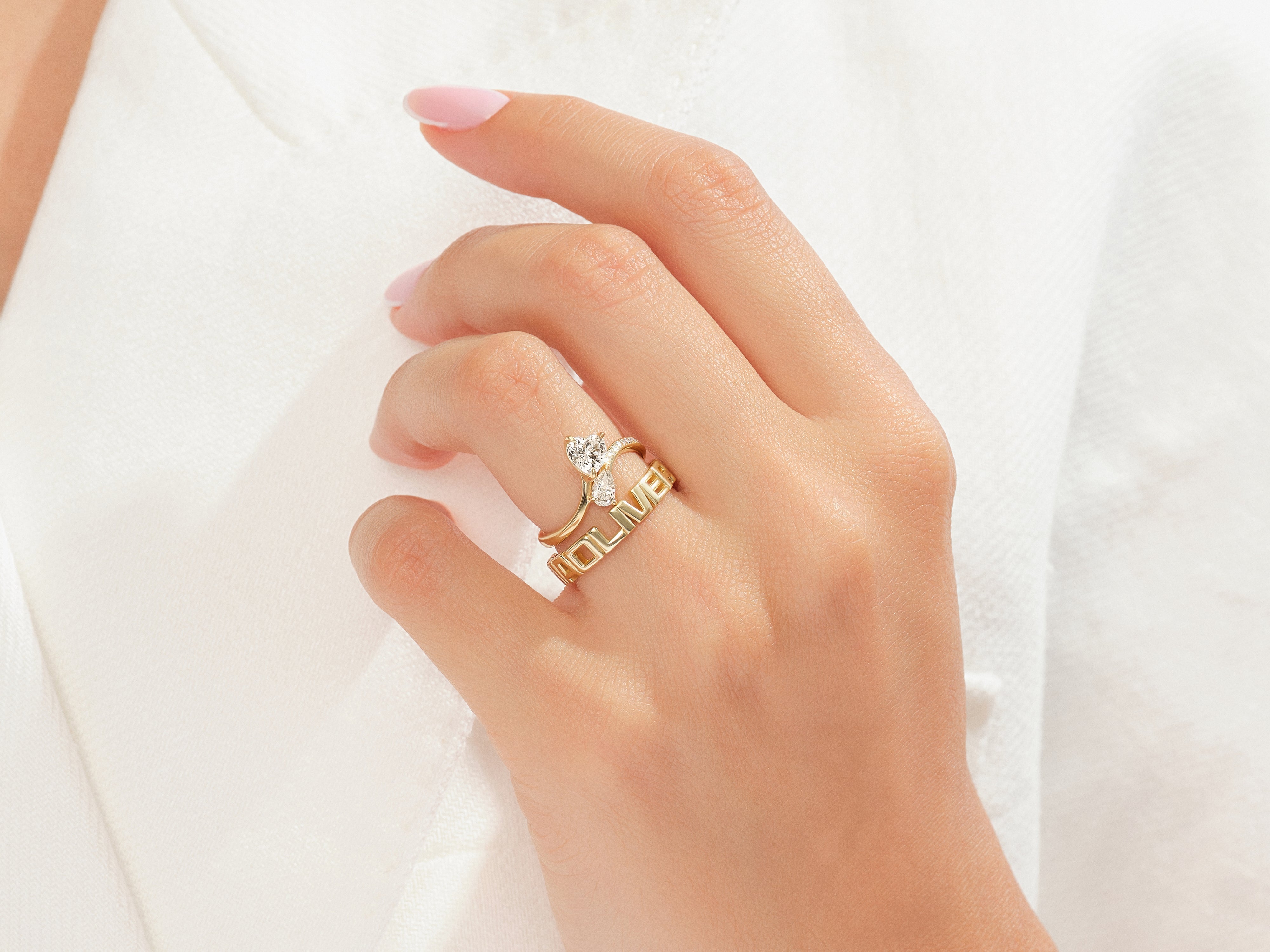 Gold rings with diamonds and "LOVE" text on a hand