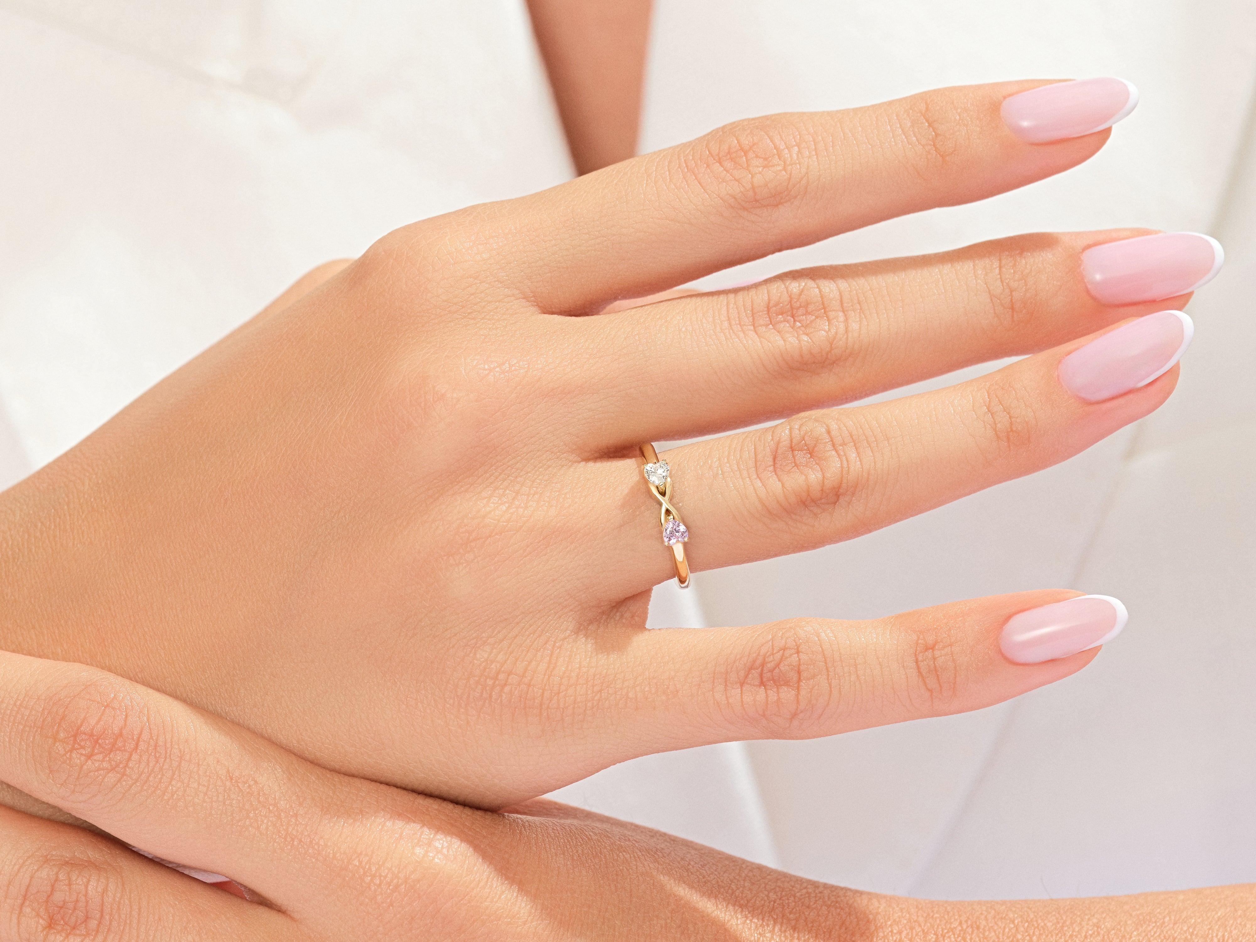 Gold infinity ring with diamond and pink sapphire on hand