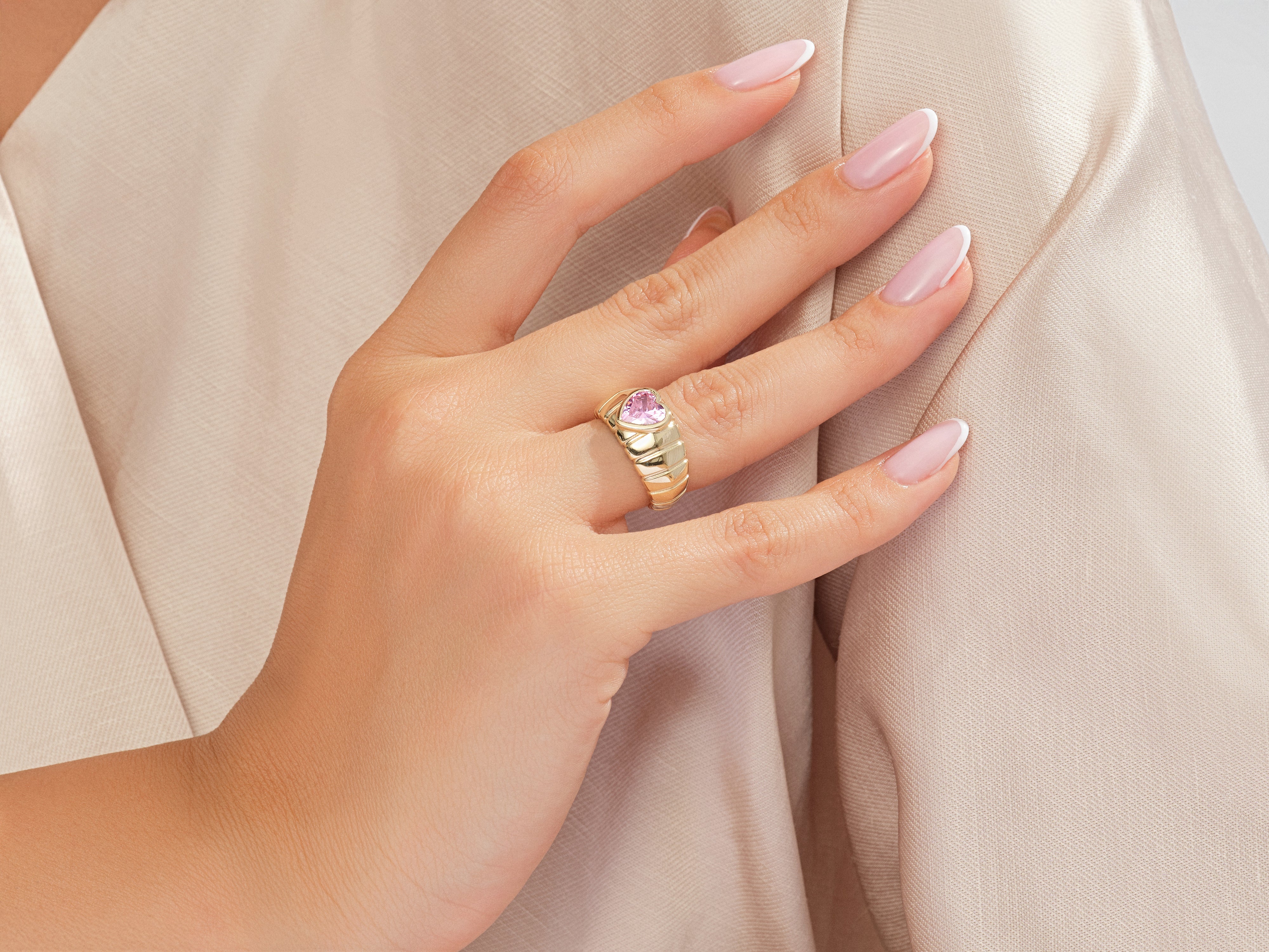 Gold ring with pink heart gemstone on a woman's hand