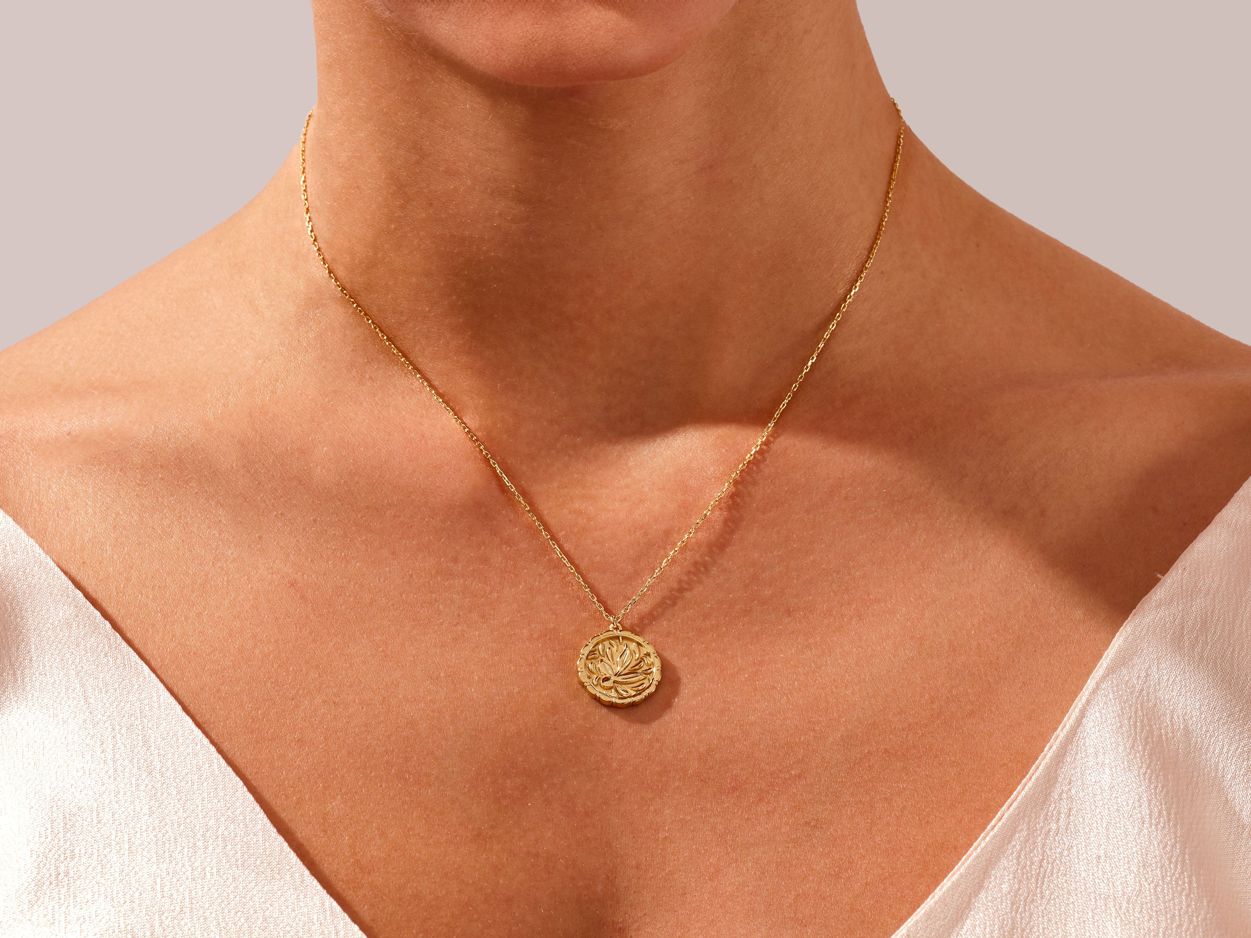 Gold lotus pendant necklace on a woman's neck