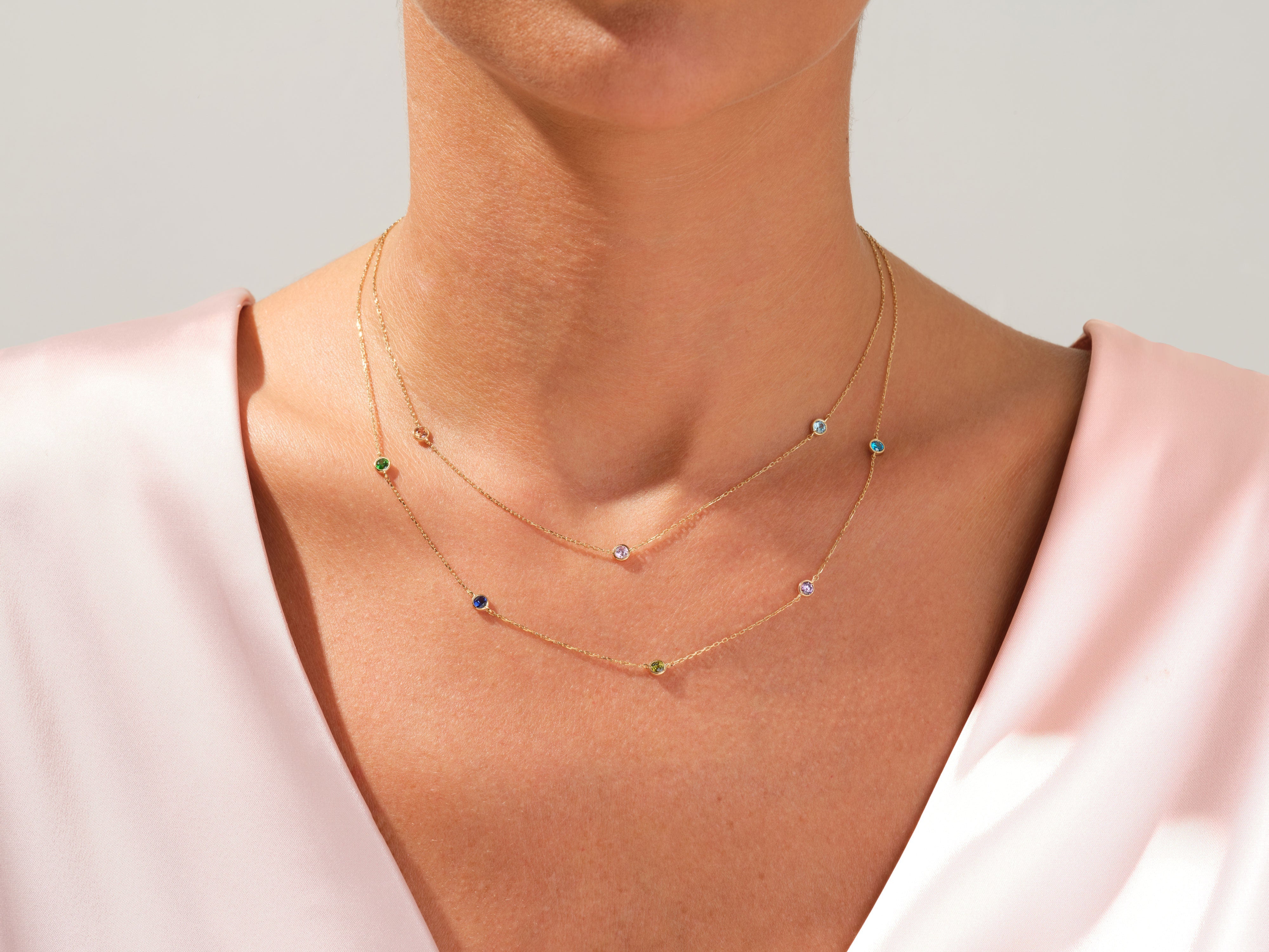 Gold necklaces with colorful gemstones on a woman's neck