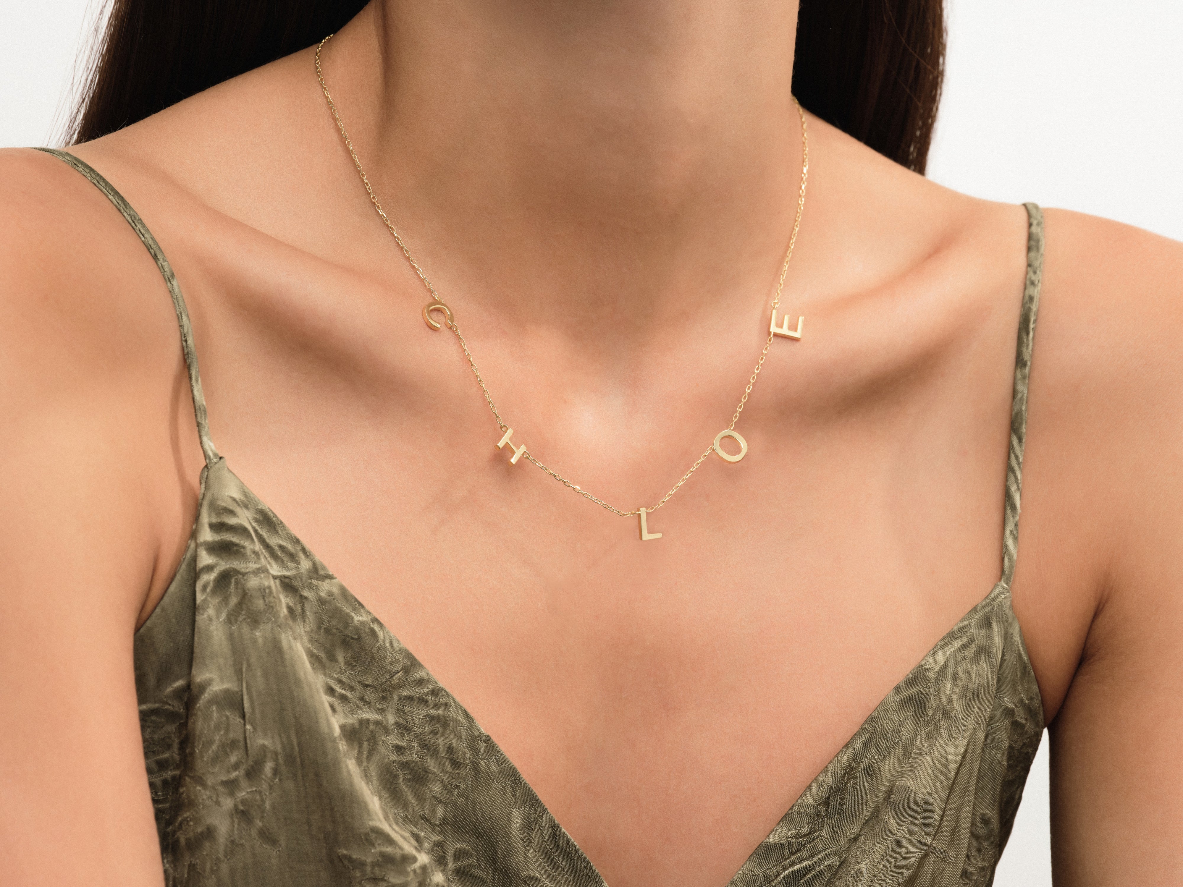 Gold letter necklace spelling "CHLOE" on a woman's neck