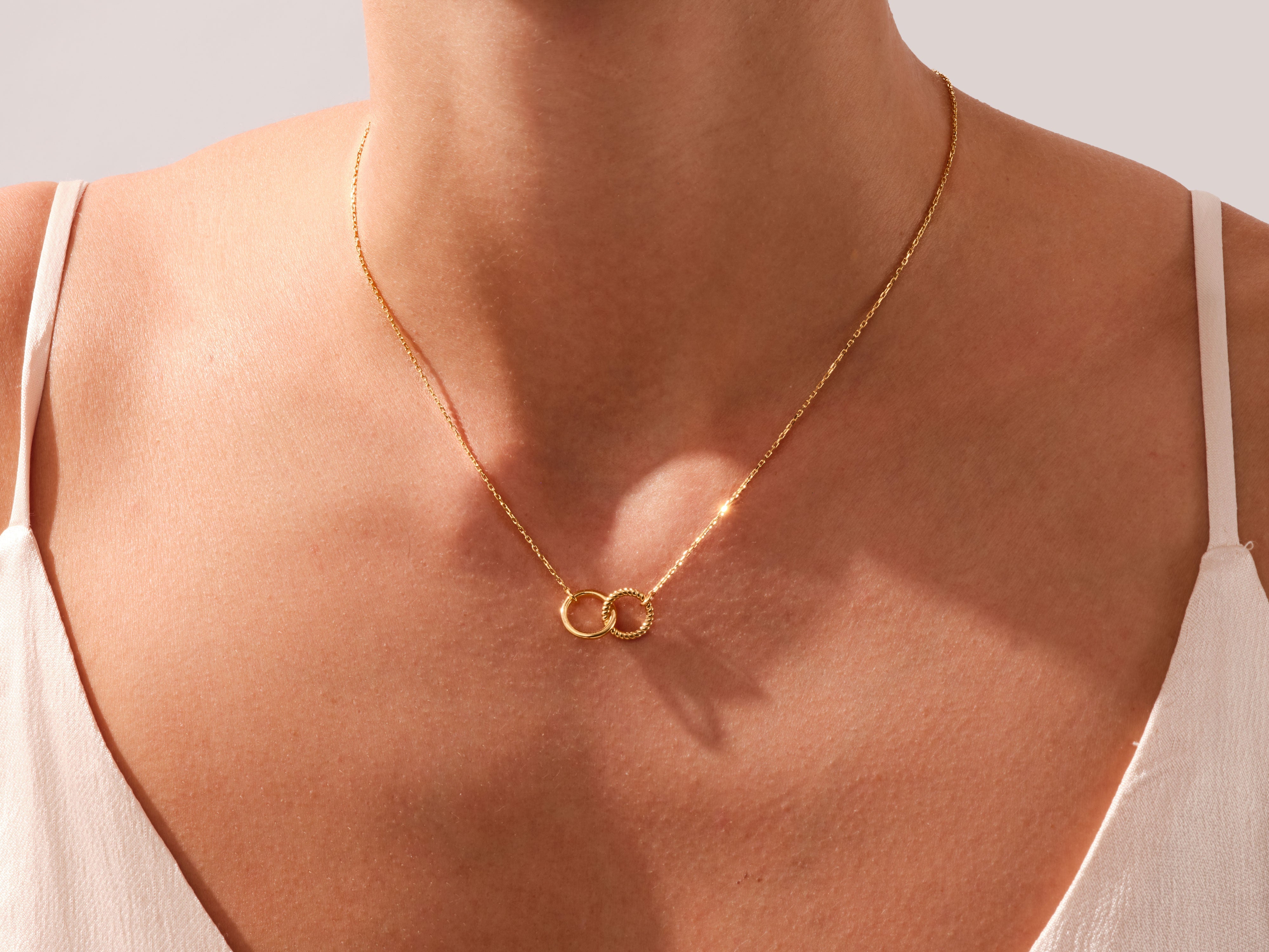 Gold interlocking circles necklace on a woman's neck