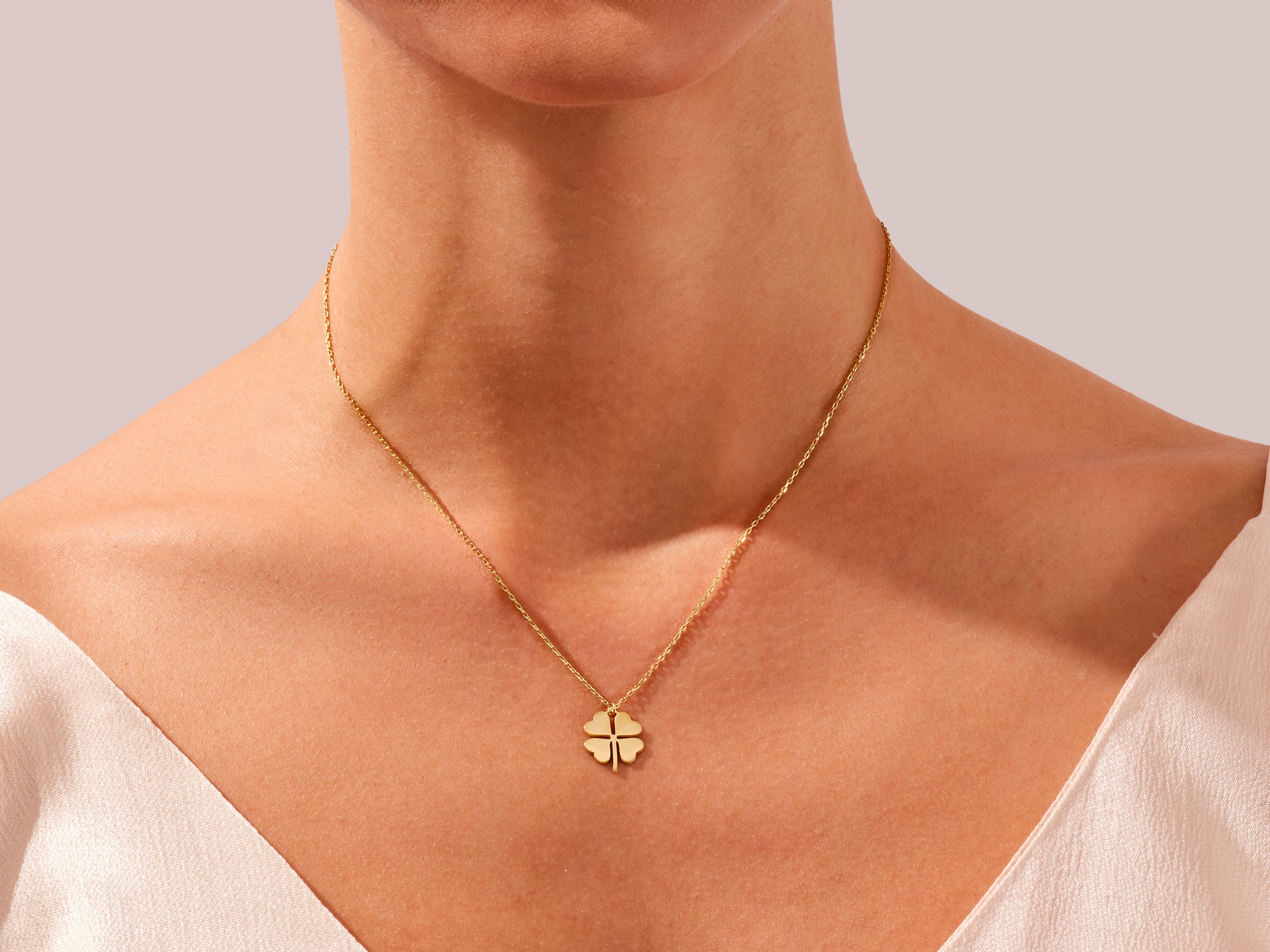 Gold four-leaf clover necklace on a woman's neck