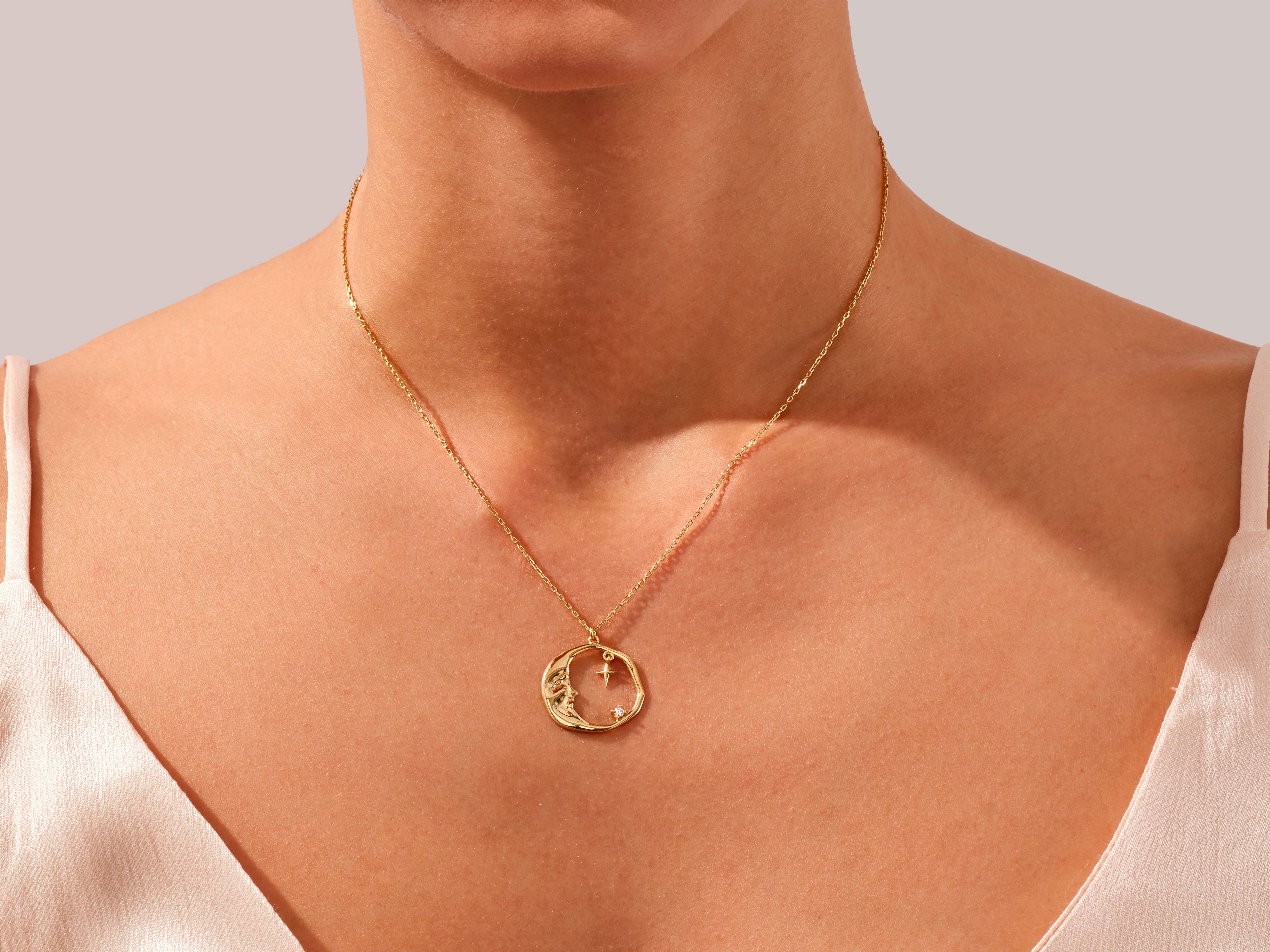 Gold moon and star necklace on a woman's neck