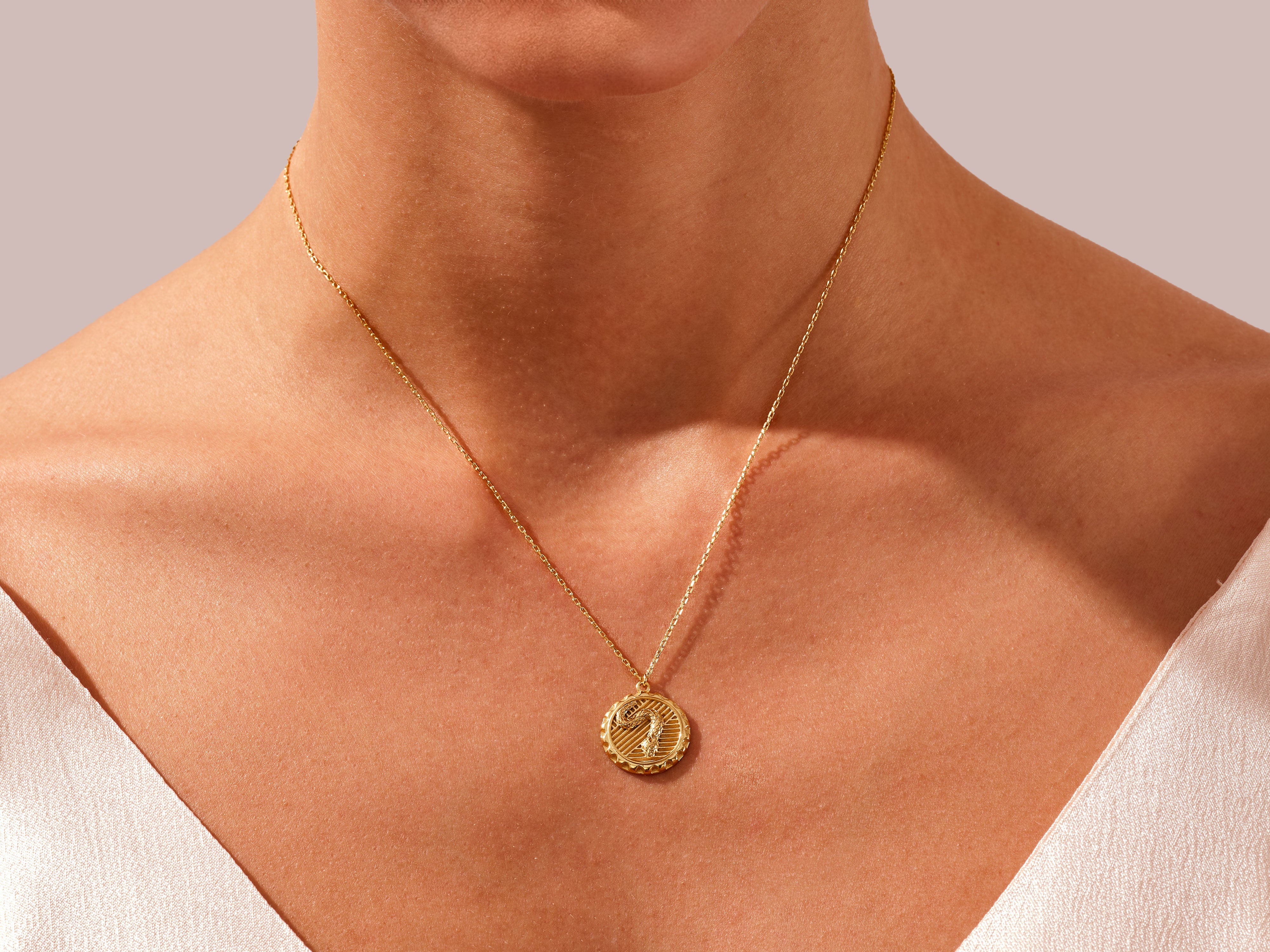 Gold snake pendant necklace on a woman's neck