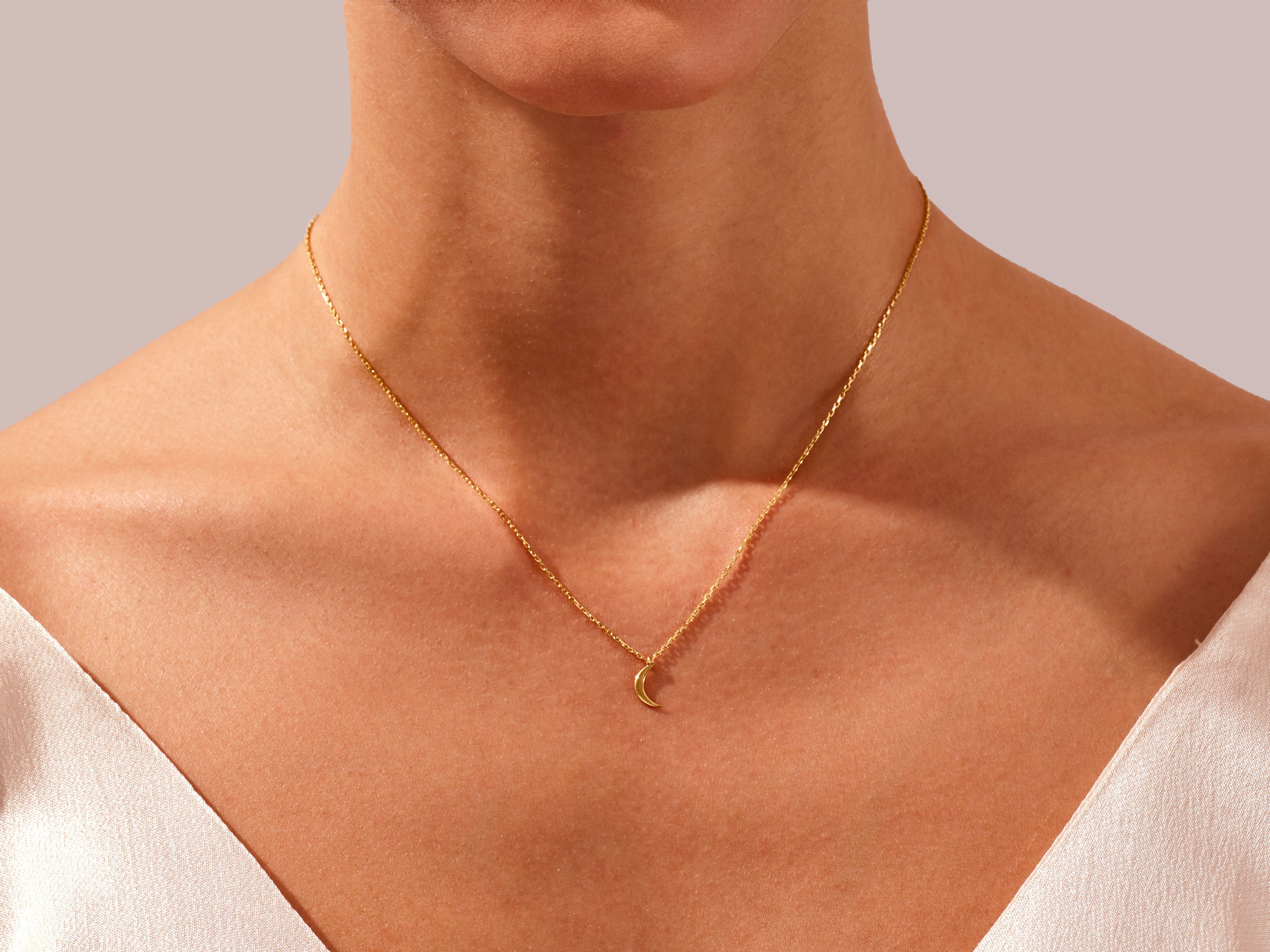 Gold crescent moon necklace on a woman's neck