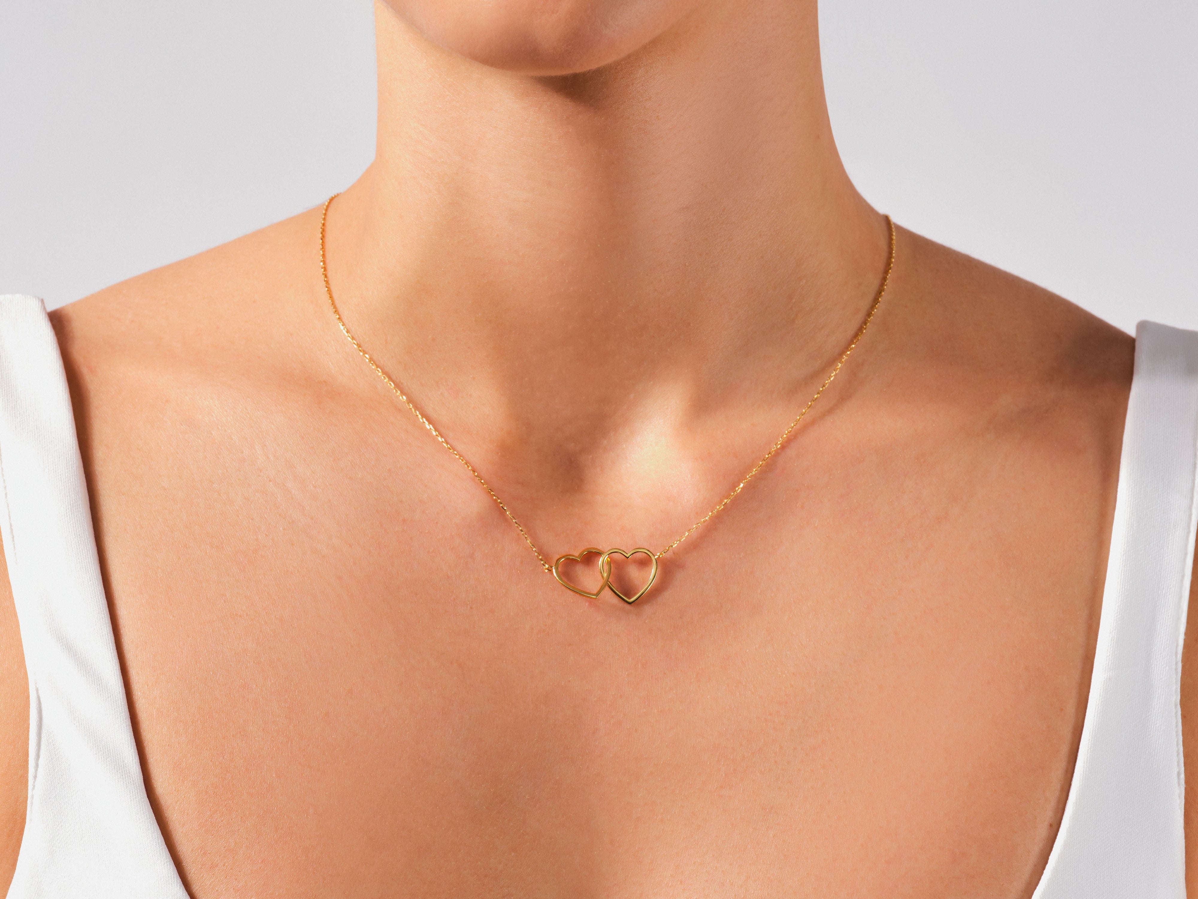 Gold interlocking hearts necklace on a woman's neck