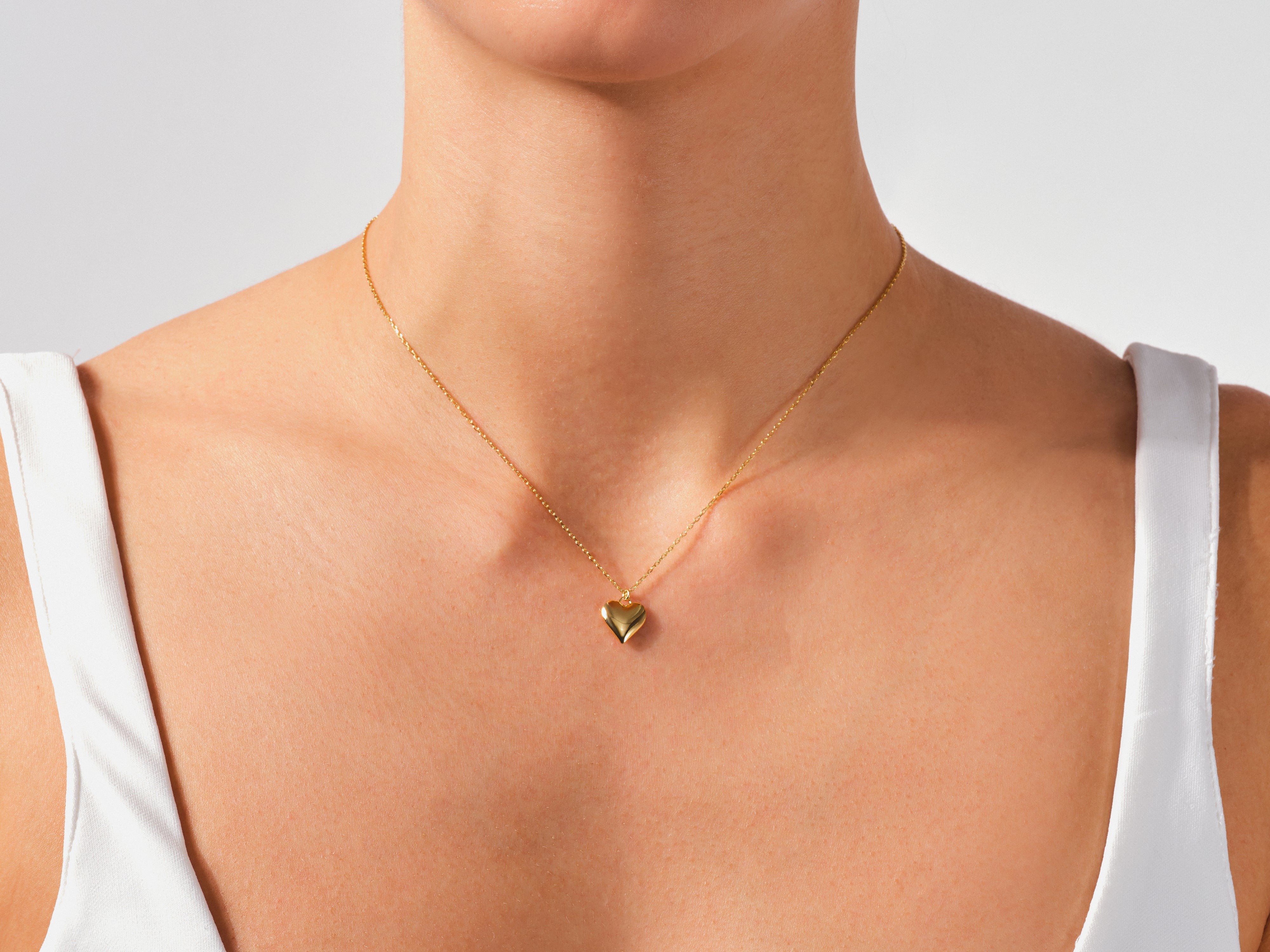 Gold heart necklace on a woman's neck, jewelry product photography