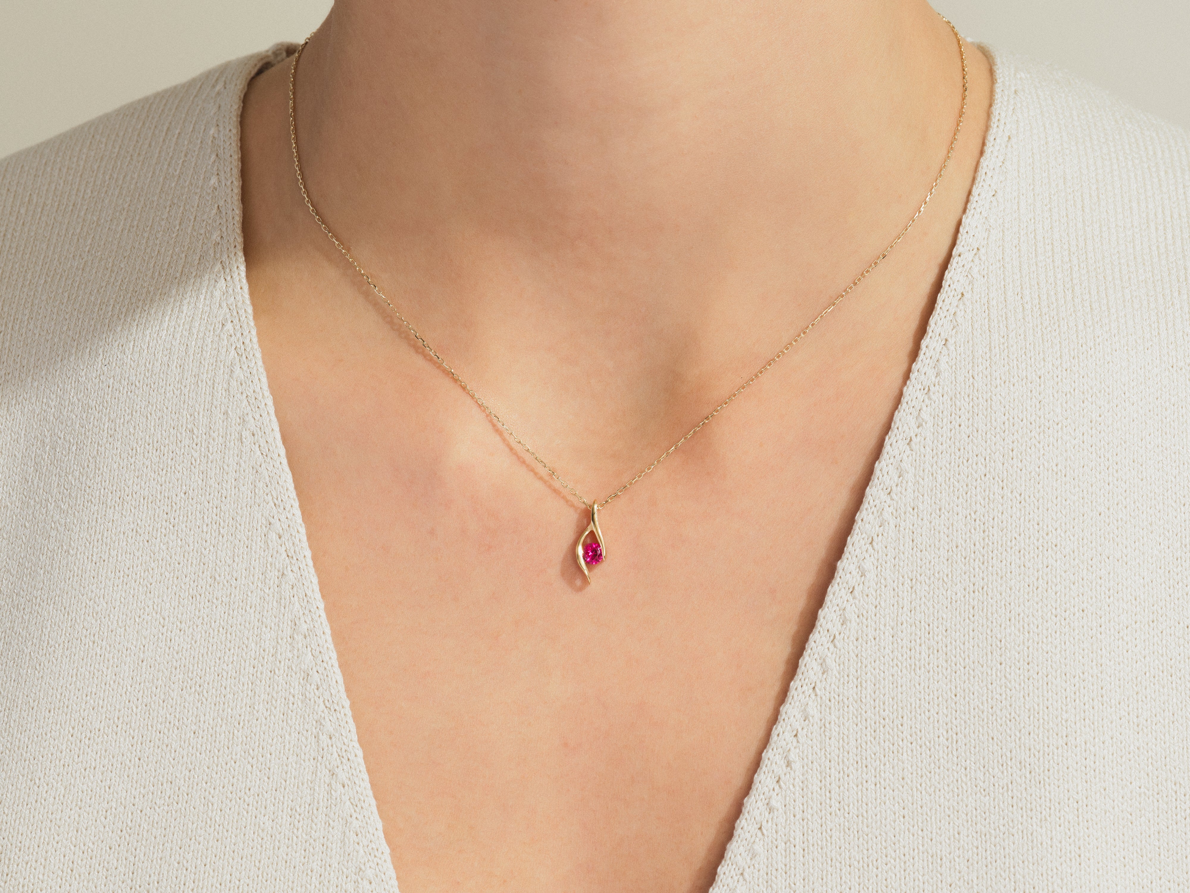 Gold necklace with ruby pendant on a woman's neck